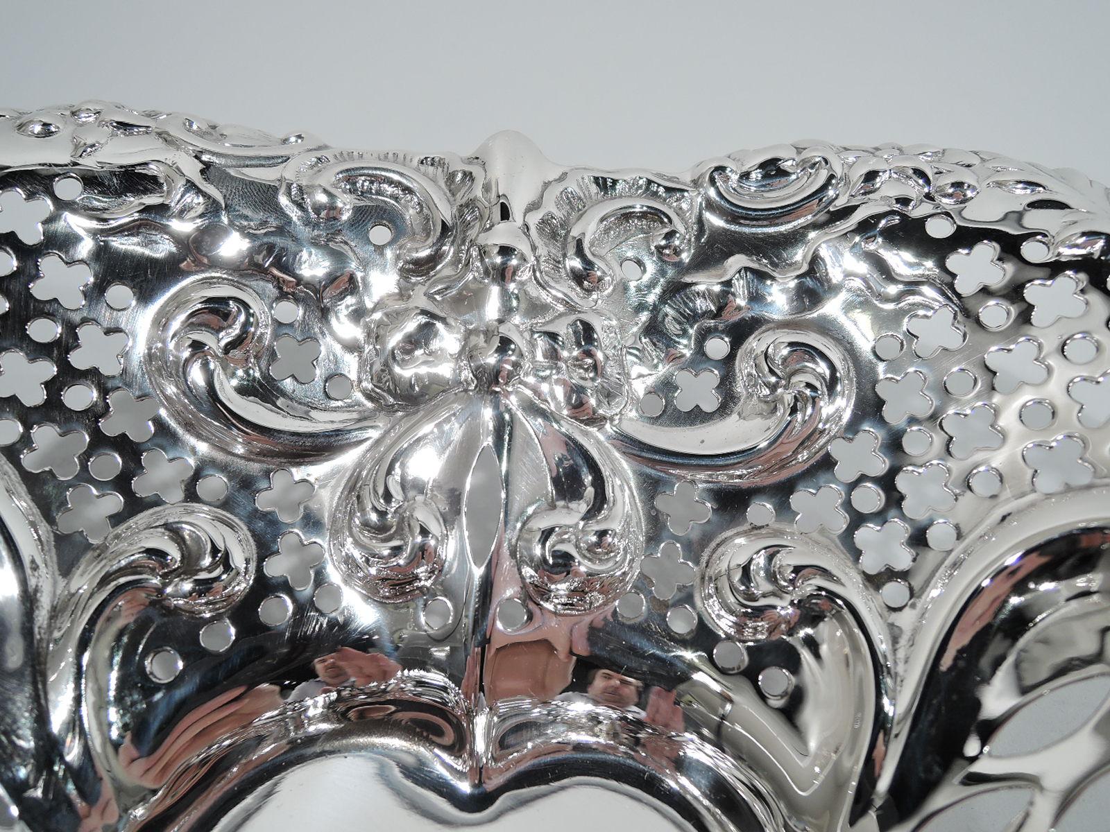 Exuberantly romantic sterling silver heart bowl. Made by Gorham in Providence in 1950. Solid well; curved and tapering sides with chased scrolls and ribbon bows, and pierced circles and quatrefoils. Irregular rim with scrolls, leaves, and flowers.