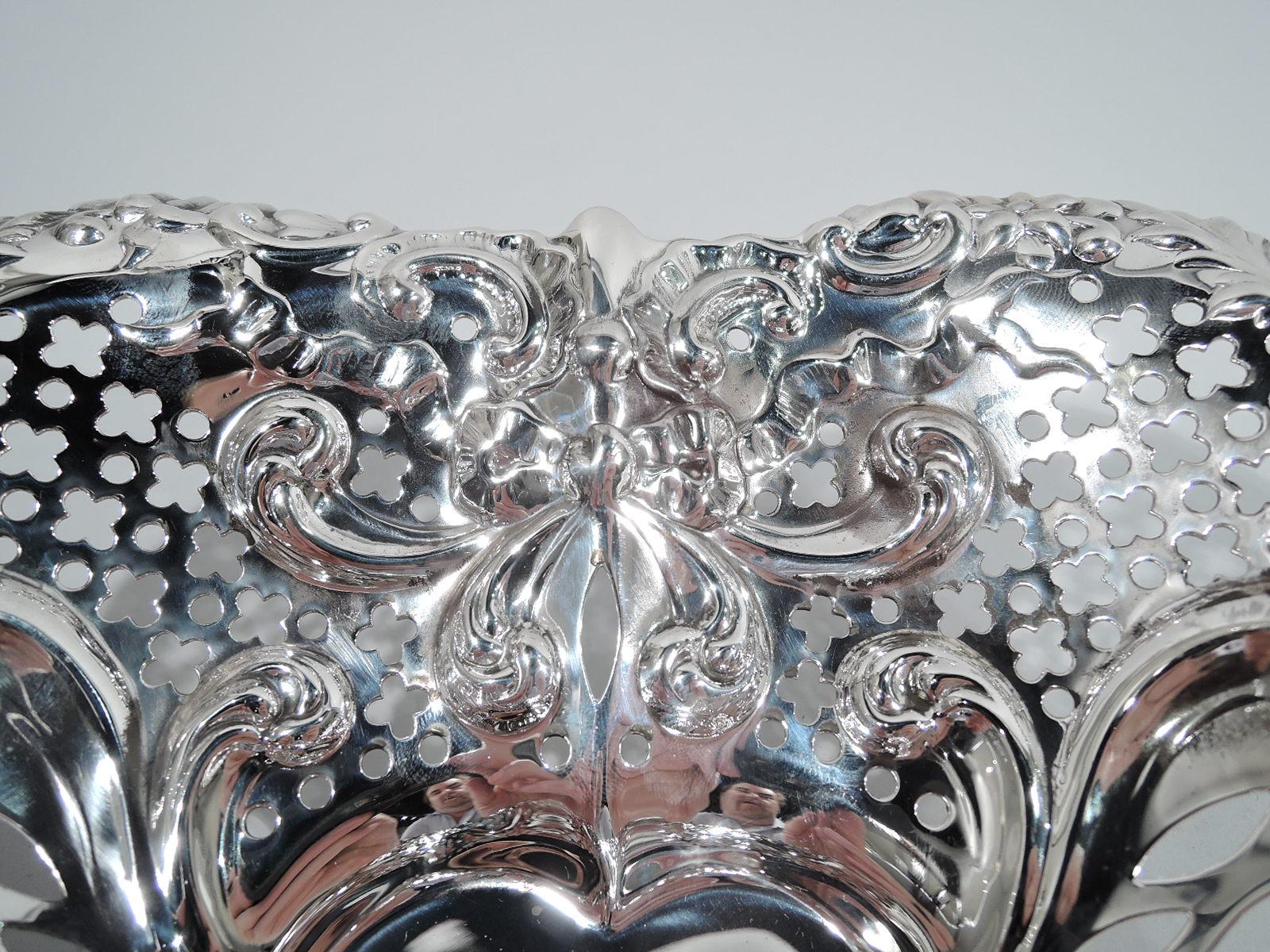 Exuberantly romantic sterling silver heart bowl. Made by Gorham in Providence in 1954. Solid well; curved and tapering sides with chased scrolls and ribbon bows, and pierced circles and quatrefoils. Irregular rim with scrolls, leaves, and flowers.