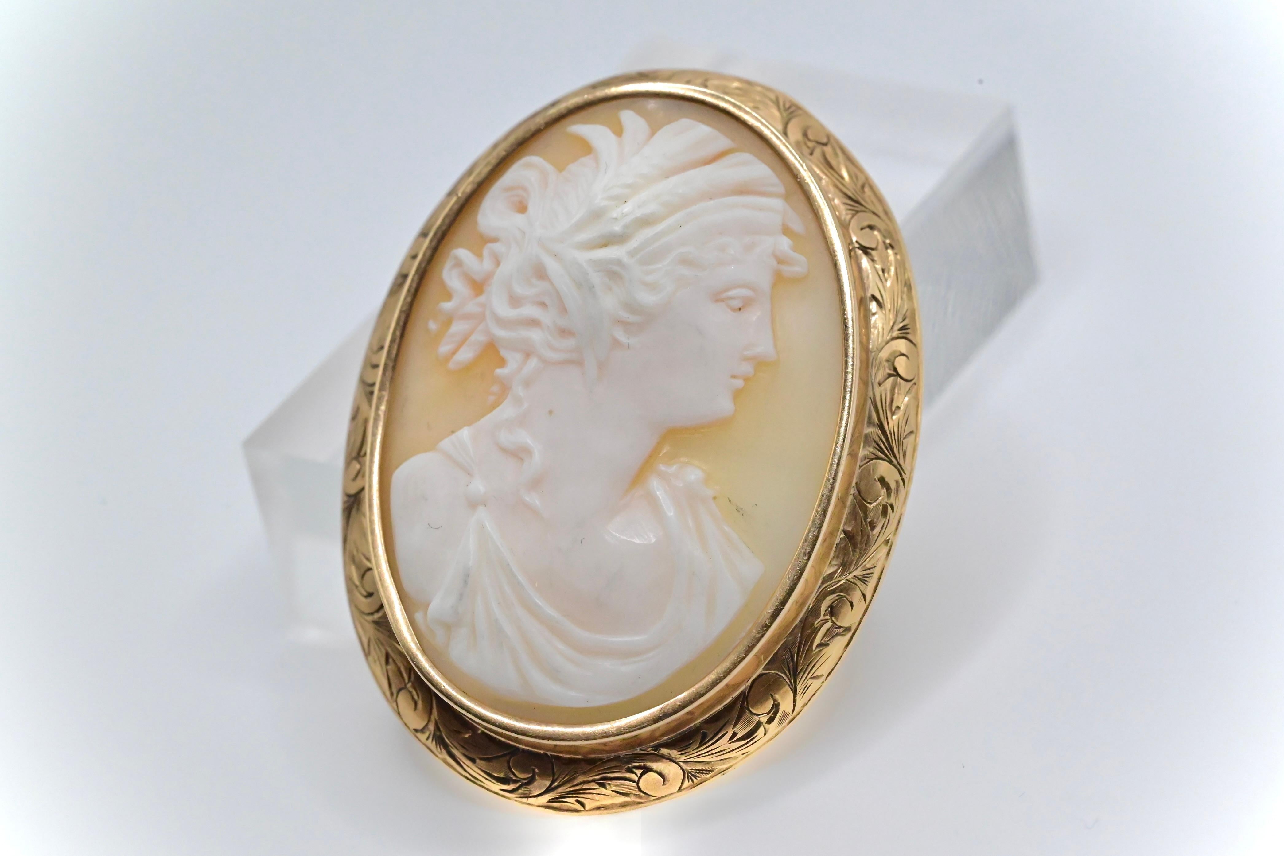 This is a beautiful carved shell cameo brooch encased in yellow gold, and has a gorgeous border. It weighs 12 grams, stands at 2 1/8 inches, and has a diameter of 1 3/8 of an inch. It’s in good condition with signs of wear that are consistent with