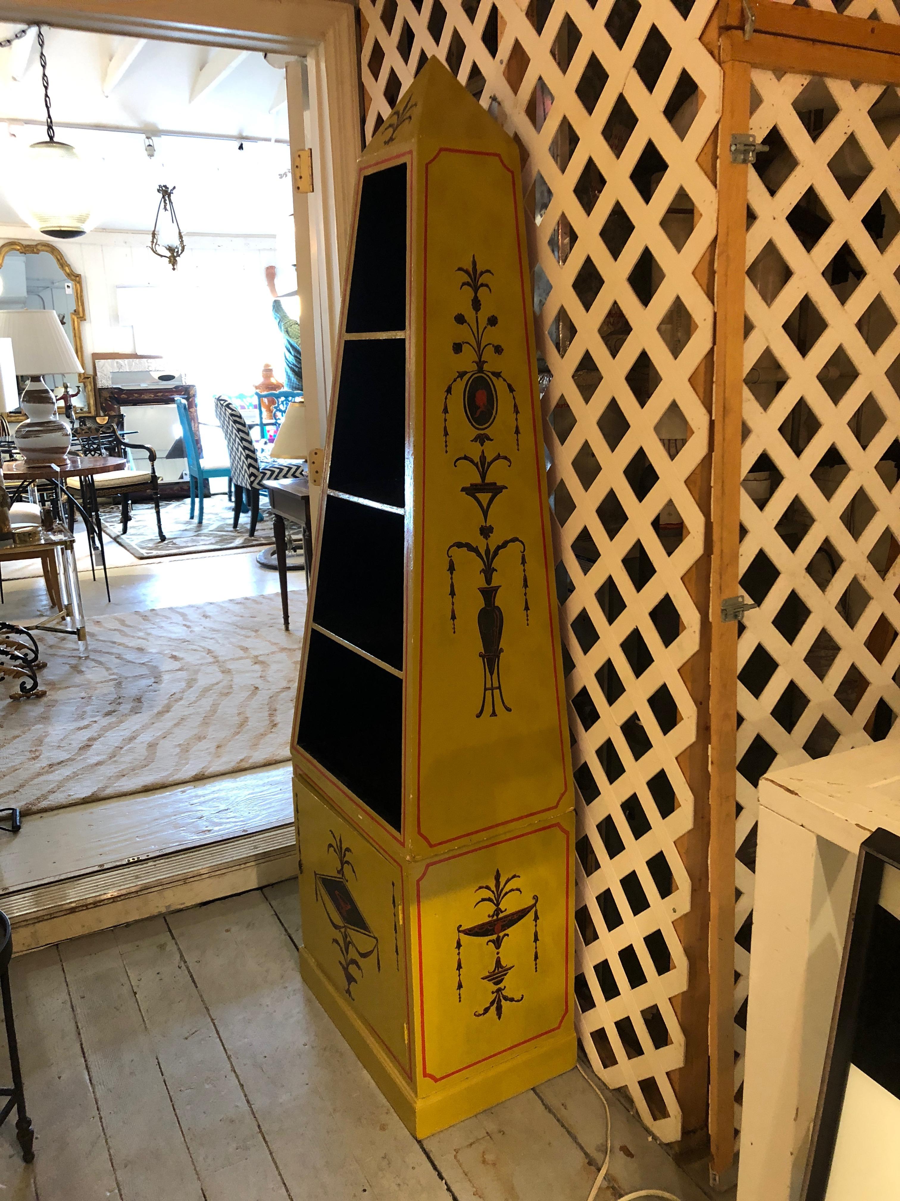 Two-piece hand painted yellow obelisk étagère and cabinet having orange red and black neoclassical decoration, interior shelves in black, and one door on the bottom that opens for storage with a bright orange red interior. No key.