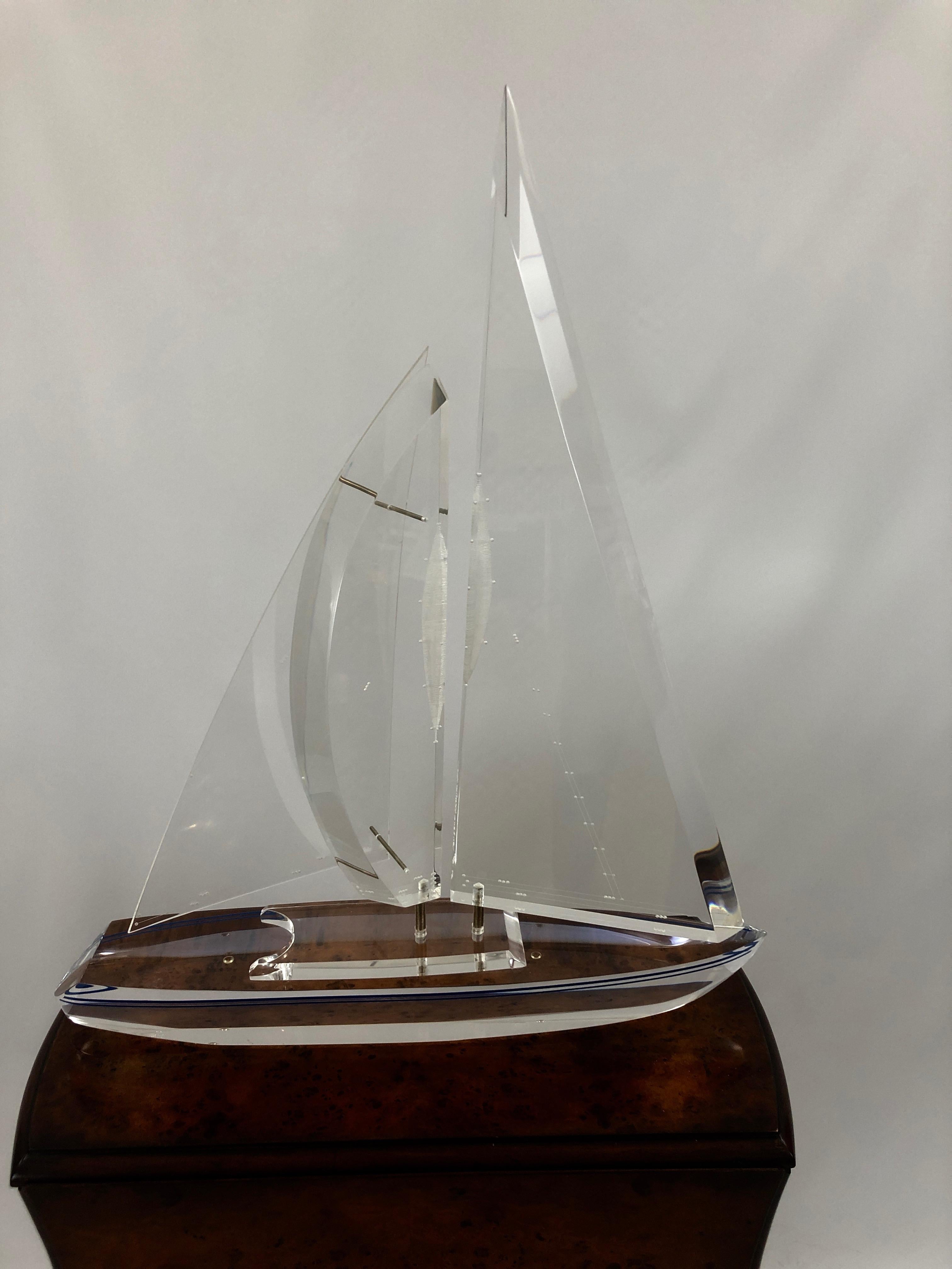 Sleek Lucite sculpture of a sailboat, signed and numbered 362/500 by Eugene Brignola. The sails move and the hull is decorated with a blue stripe.