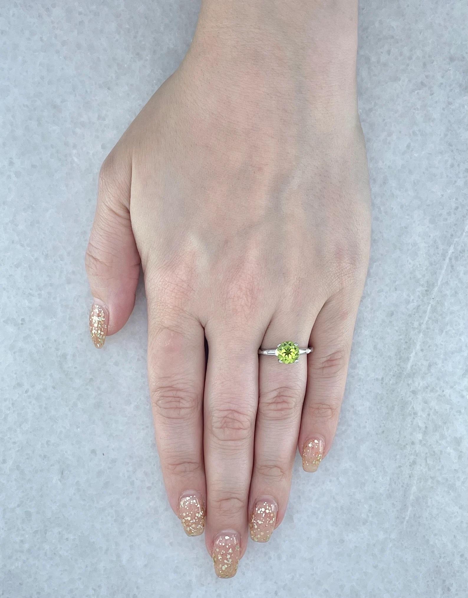 A beautiful vintage peridot and baguette cut diamond three stone ring in platinum. Centered by a 2 carat old European cut peridot of beautiful vivid green color this ring also features two accenting tapered baguette cut diamonds. Grading as G color