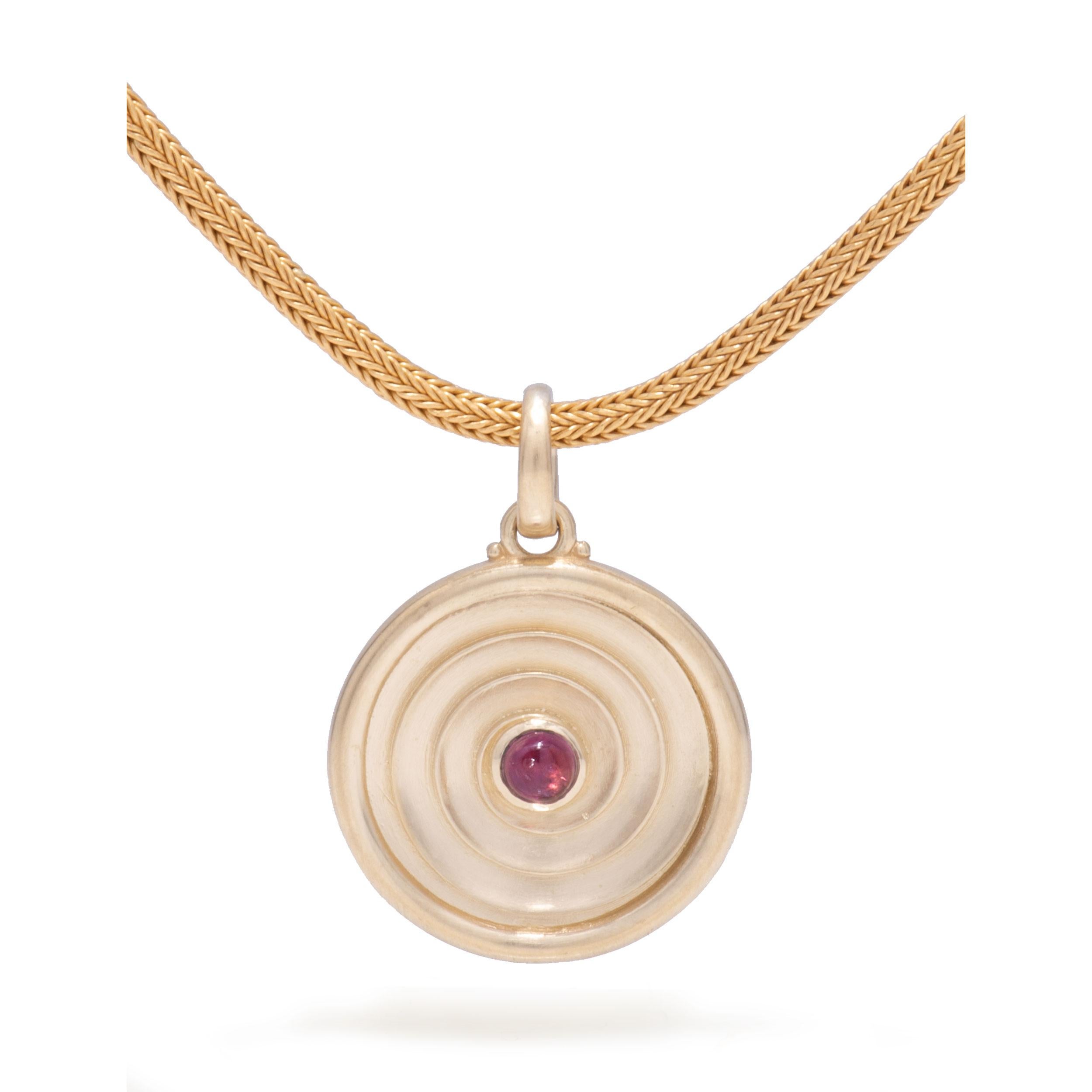 The Eye of Horus symbolizes royalty, protection and health. Crafted in 18 karat gold, a spiral on one face is centered with an eye of pink tourmaline cabochon. On the reverse, an Eye of Horus emerges from the center of this mysterious gold pendant.
