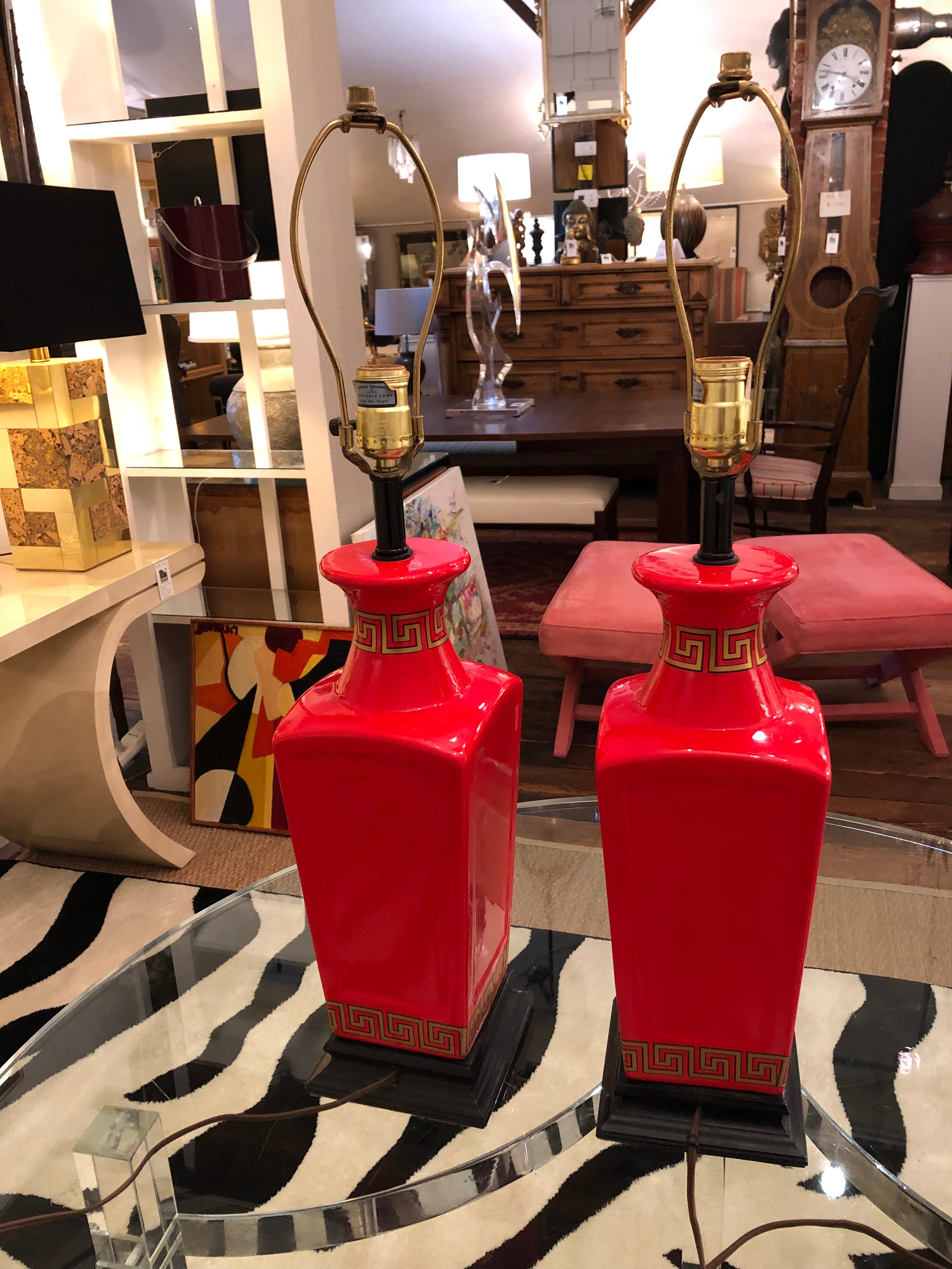 Eye poppingly glamorous pair of Hollywood Regency bright red Chinese style lamps having gold Greek key decoration and black bases. Bases are 5.5