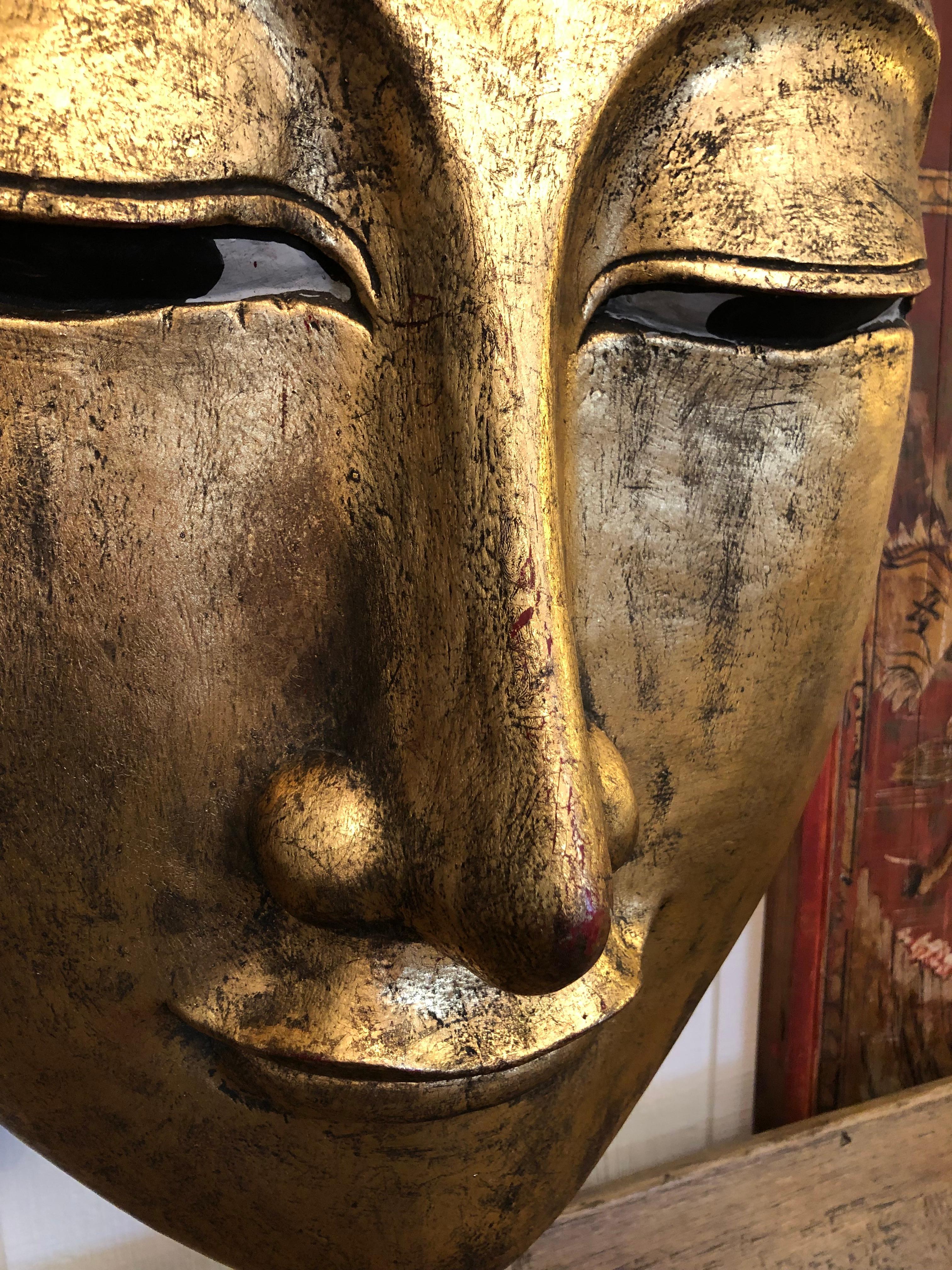 Sensational eye poppingly glamorous and huge gilded carved wood head of a Buddha that hangs as wall art.  Incredibly detailed with serene facial expression, hundreds of circular raised embellishments around the crown, and inlaid bits and pieces of