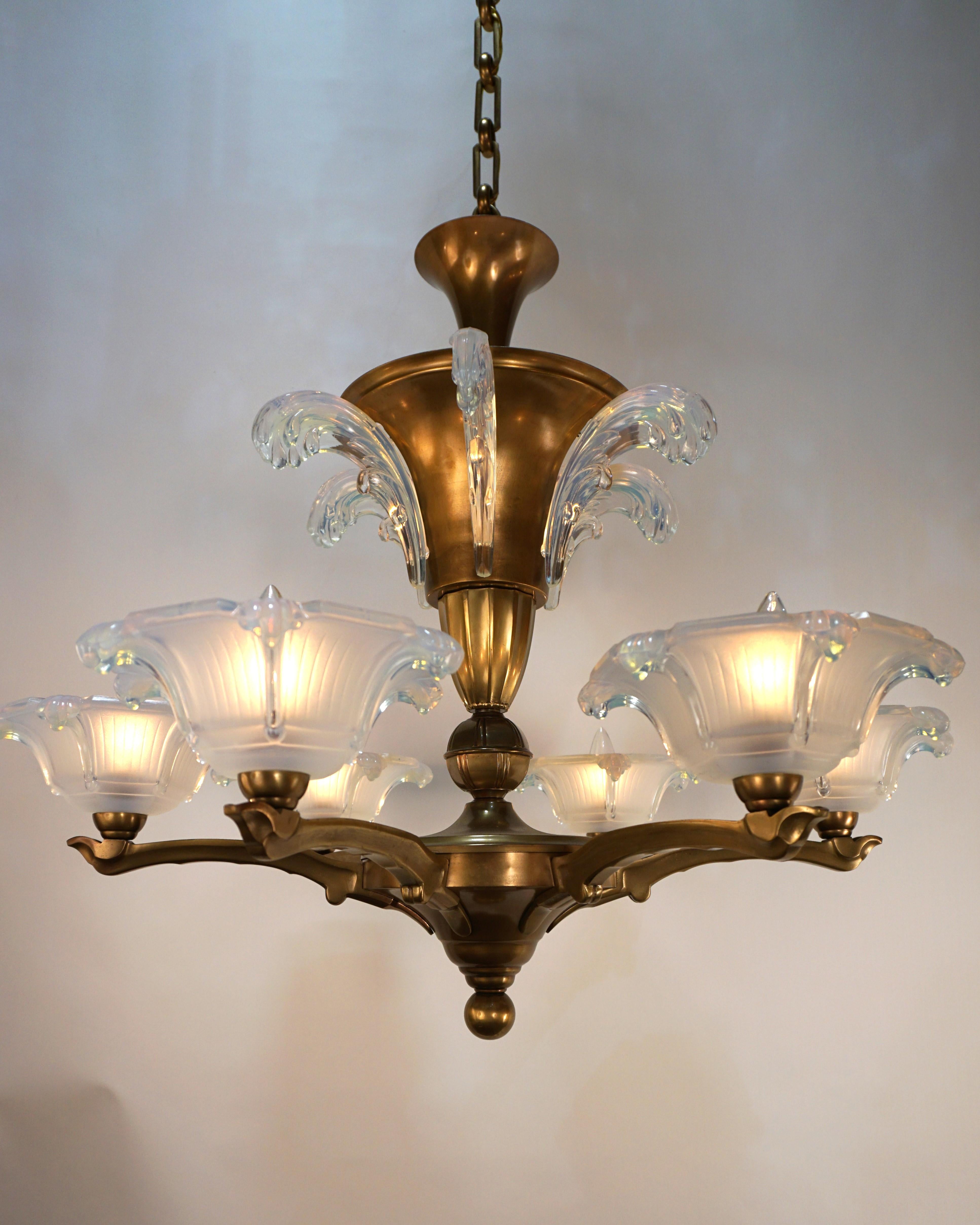  Petitot und Ezan - Art Deco Kronleuchter aus den 1930er Jahren ist ein eleganter Kronleuchter im Bronzedesign mit schönen hellen honigblauen Glasschirmen. 
Professionell neu verkabelt und einbaufertig.
Sechs Arme, acht Leuchten, je 60 Watt