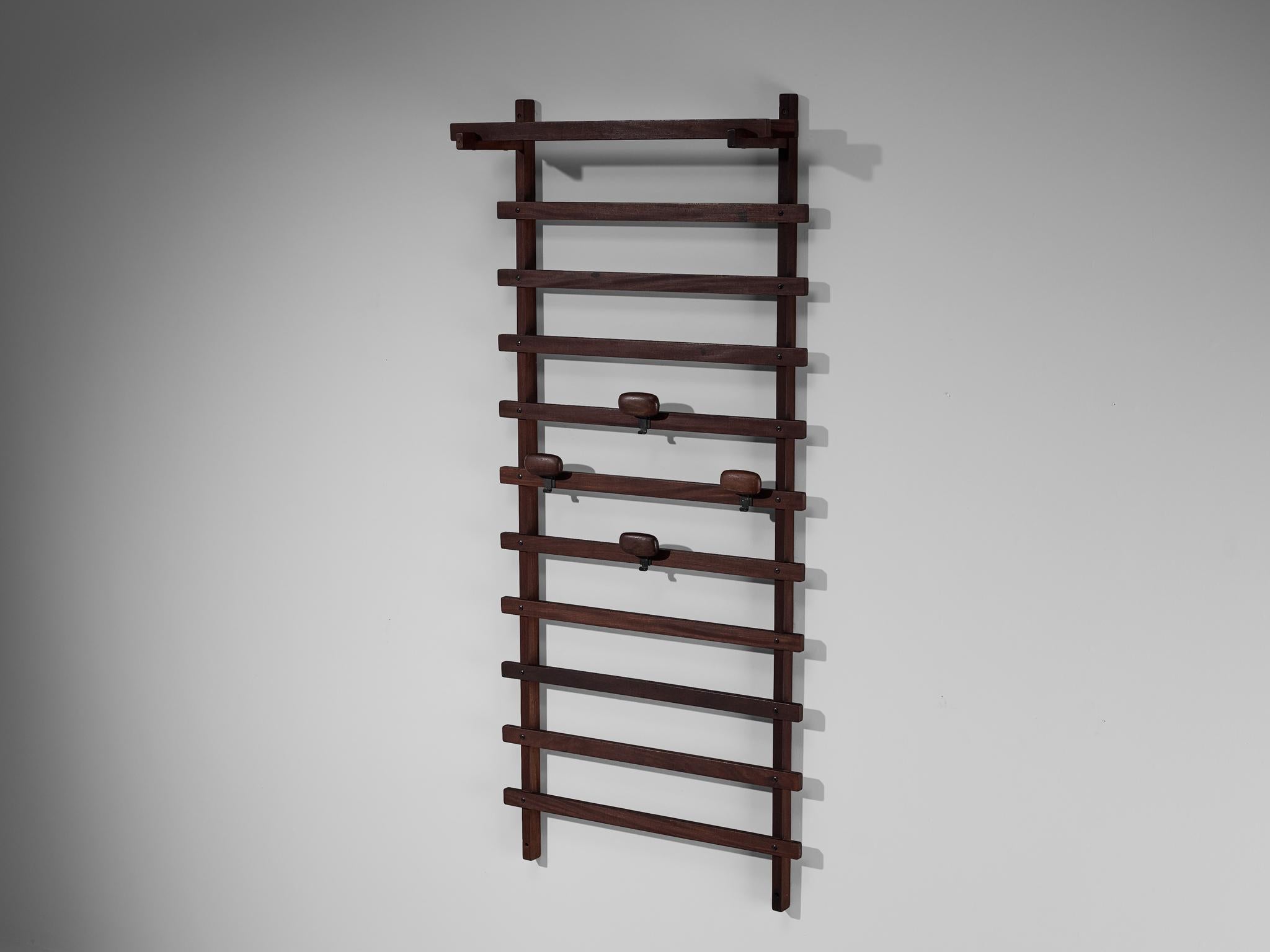 Ezhio Longhi for Elam, wall-mounted coat rack, teak, metal, Italy, circa 1961.

This hallway setting is designed by Ezhio Longhi for Elam and is executed in solid teak. While maintaining a simplicity in form, the design is distinguished by