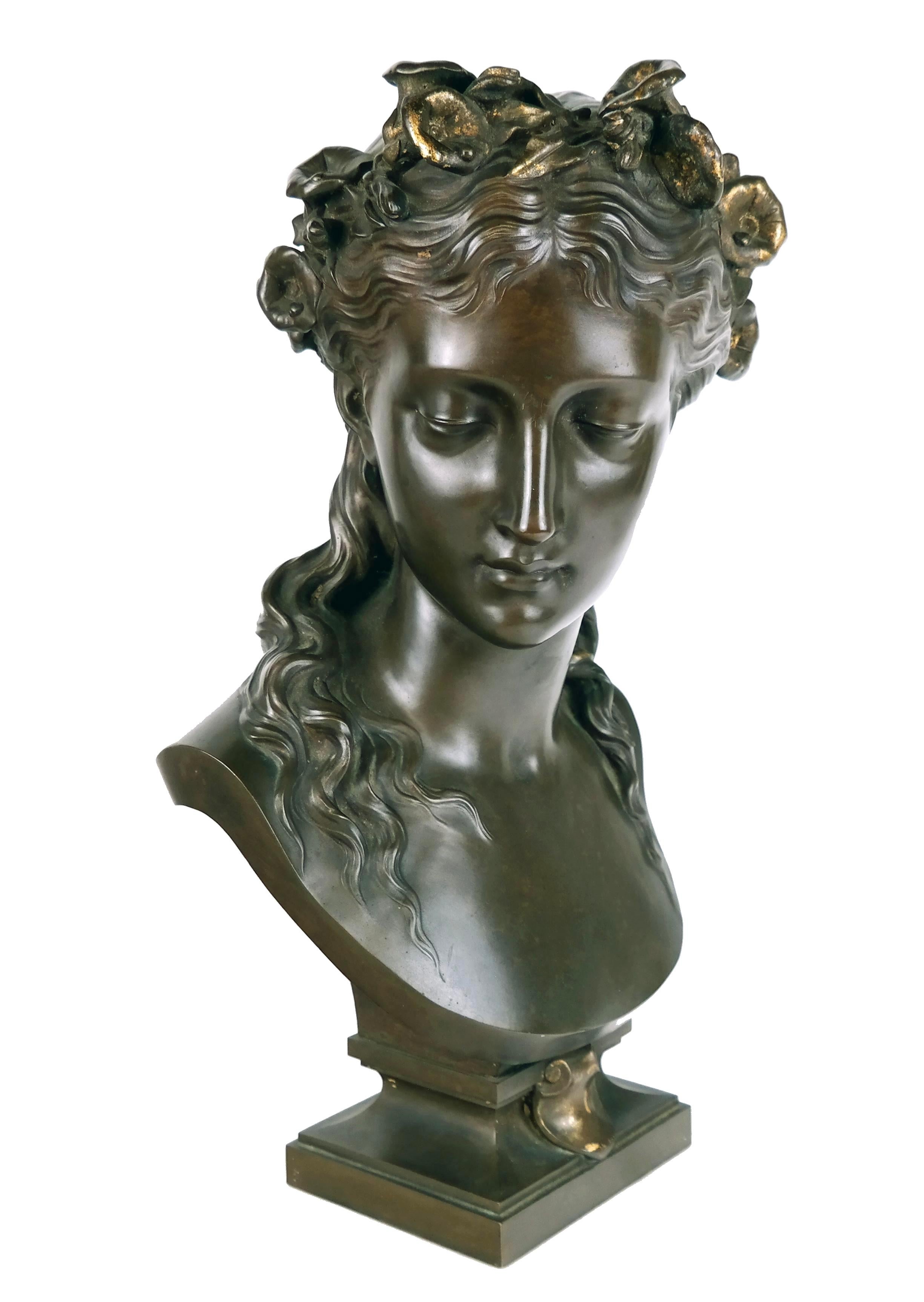 Busto di bronzo di donna del XIX secolo di Ferdinand Barbedienne (1810-1892). Il busto presenta la testa di una donna con capelli lunghi e ondulati, ornata da una corona floreale. La sua espressione è serena e la sua corona floreale simboleggia la