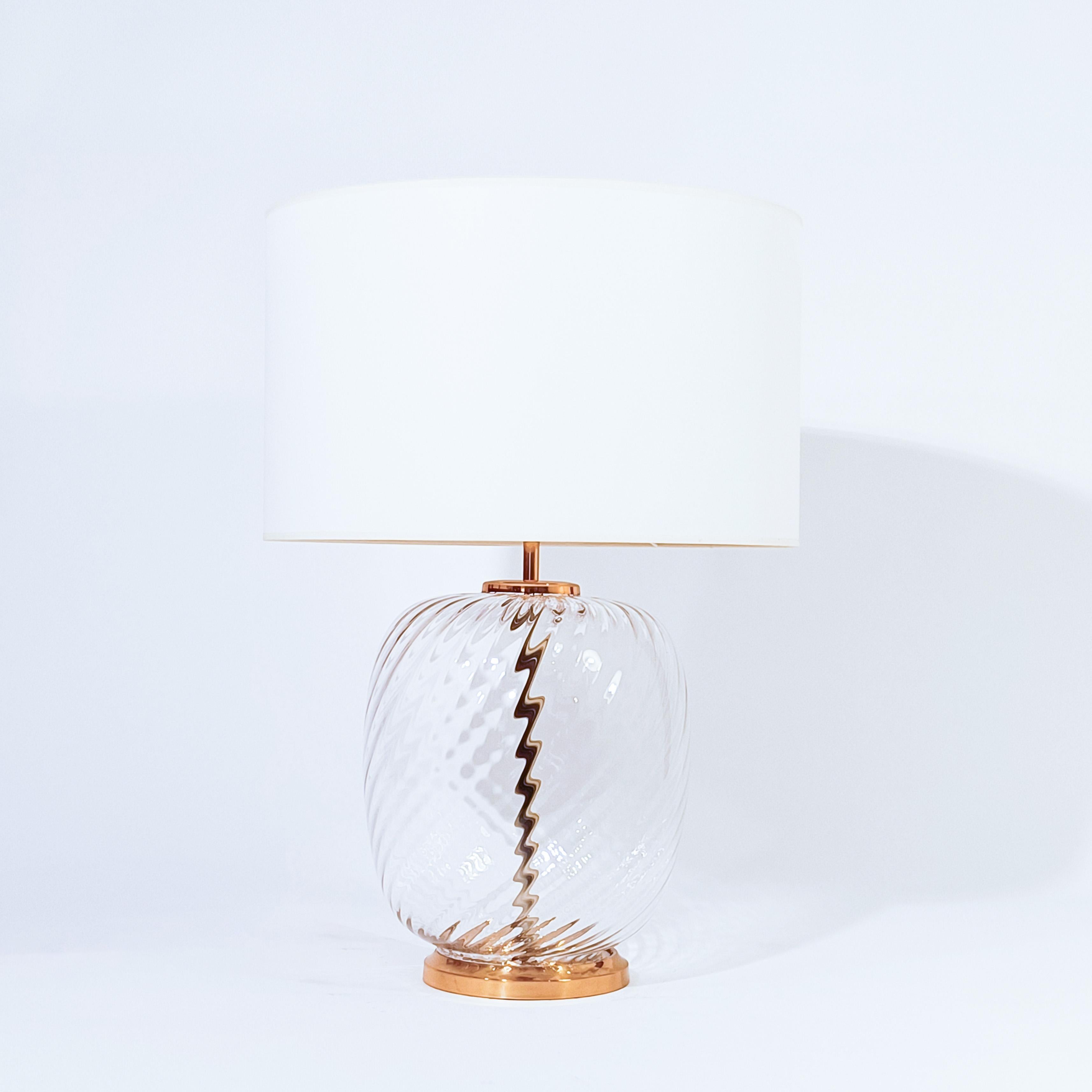 Post- Modern and Hollywood Regency style Murano glass table lamp in the style of F. Fabbian, Italy, 1970s. Formed by a single piece of transparent hand-blown Murano glass in a swirling shape. Structure and base in golden chrome metal and brass.