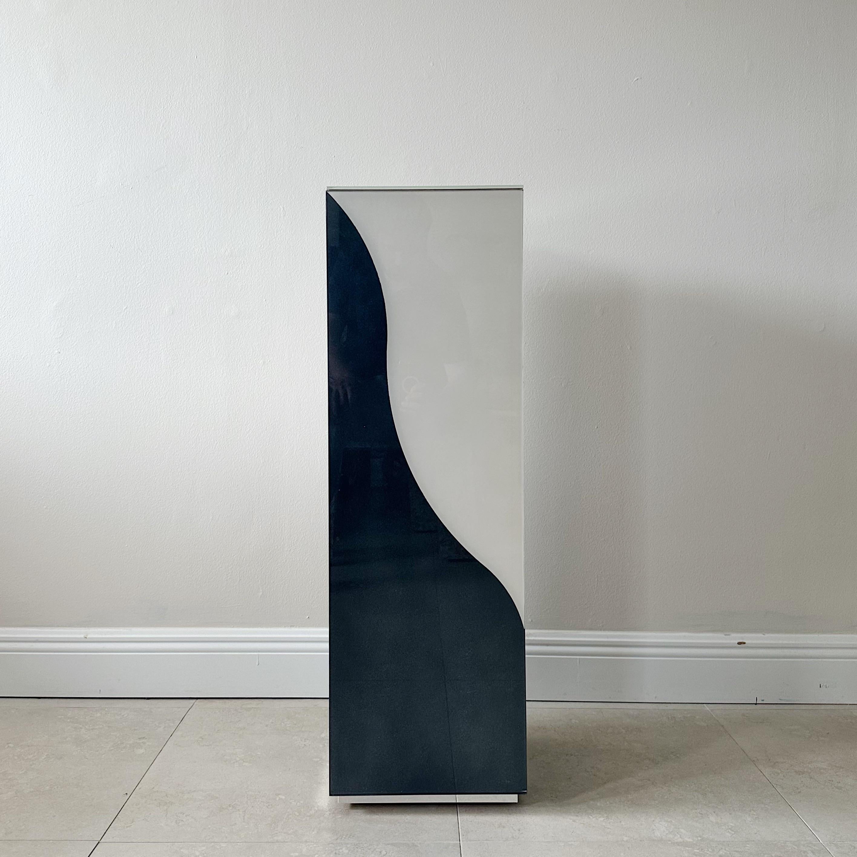 A tall rectangular pedestal from the 1970s, with wavy black and white bonded colored glass. This exceptional piece of furniture is attributed to either F. Hayman Chaffey for Directional, both known for their iconic mid-century designs. The wavy