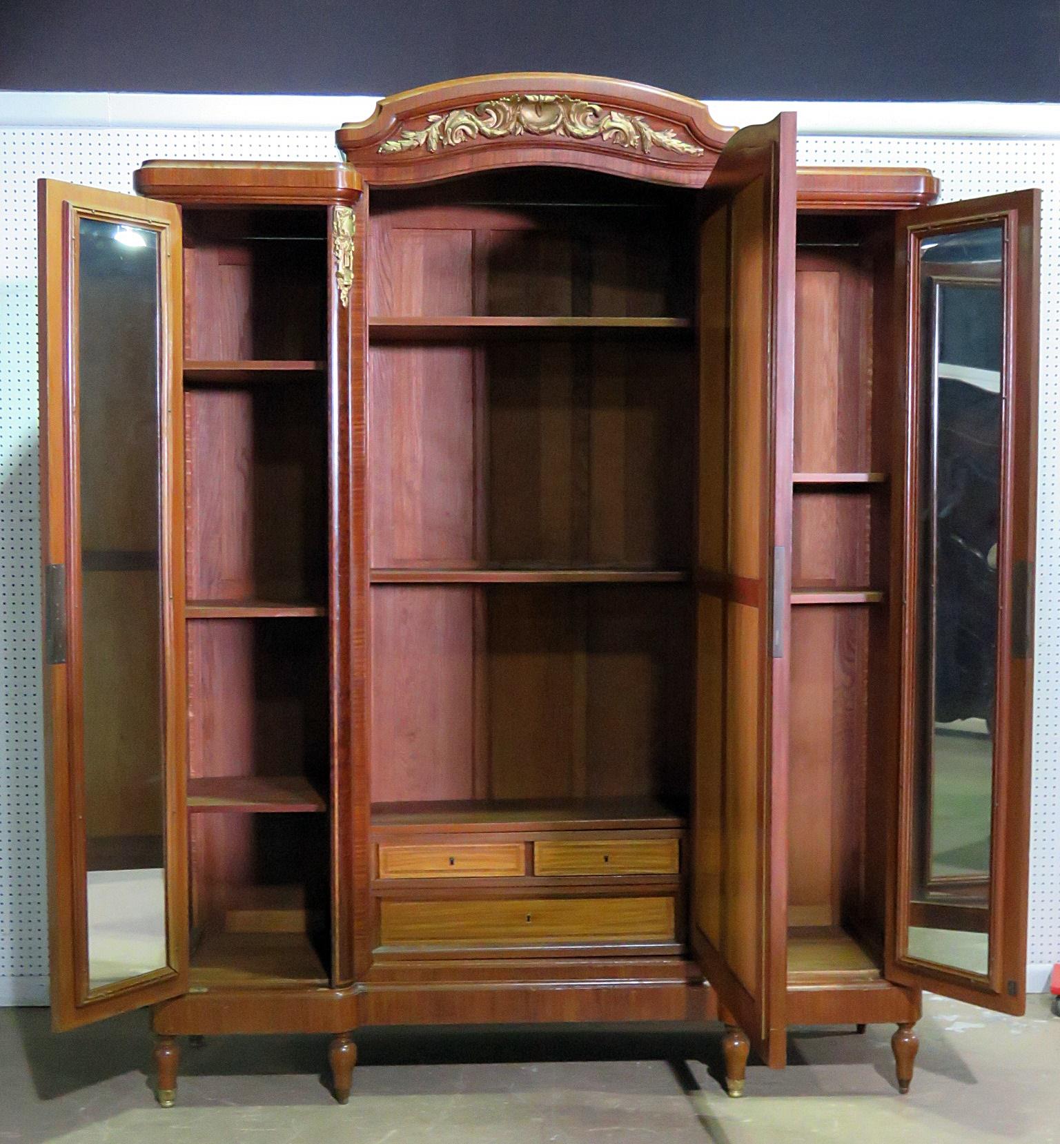 F. Linke style inlaid armoire with bronze accents. The center door has a beveled mirror and contains 2 shelves. The left door contains 3 shelves and the right door contains 2 shelves. Both side doors are mirrored internally.