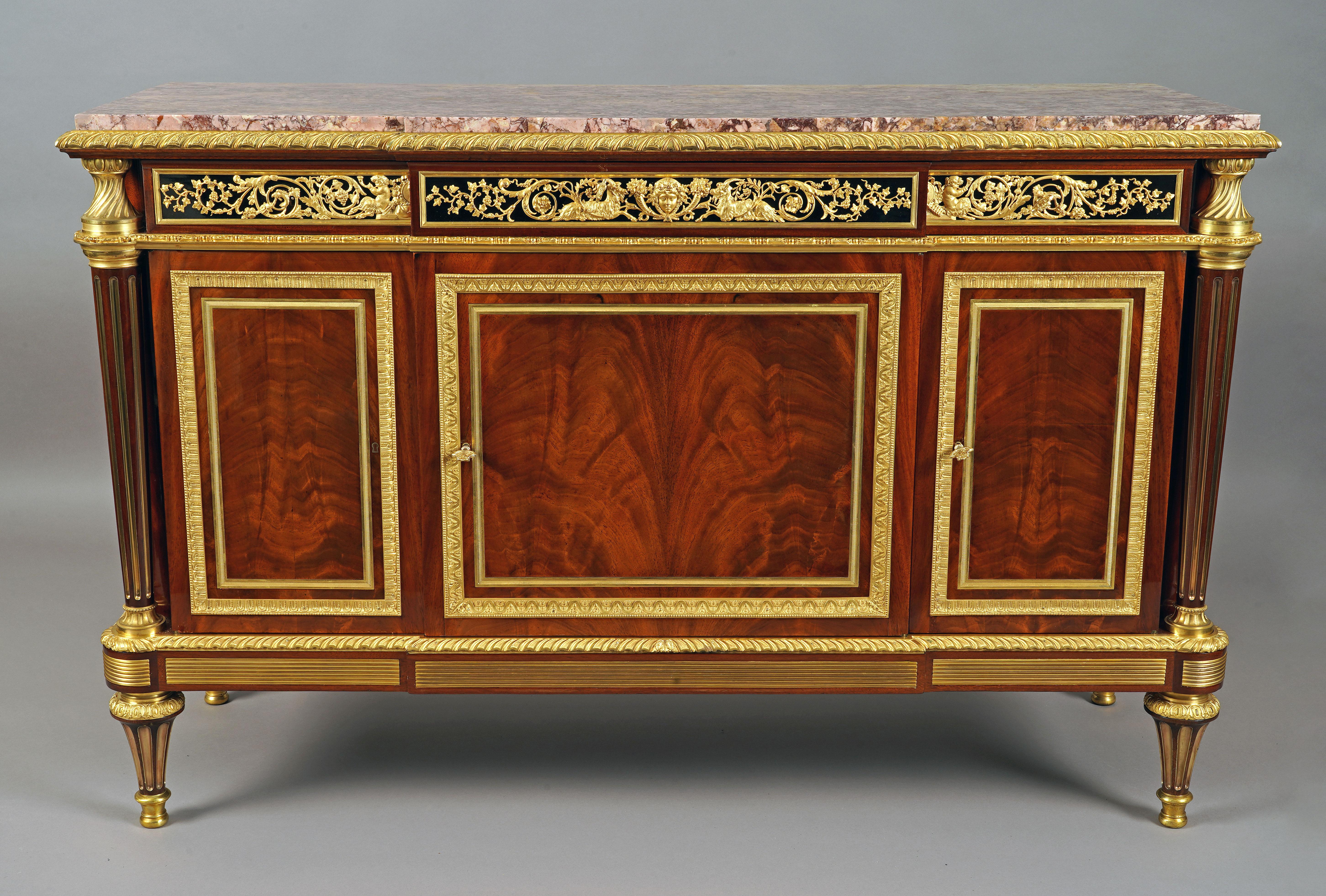 Beautiful Louis XVI style commode opening with three doors topped with drawers decorated with rich and fine ornamentation in chased and gilded bronze of female masks, ibexes and young satyrs among foliage scrolls and vine branches on a blackened