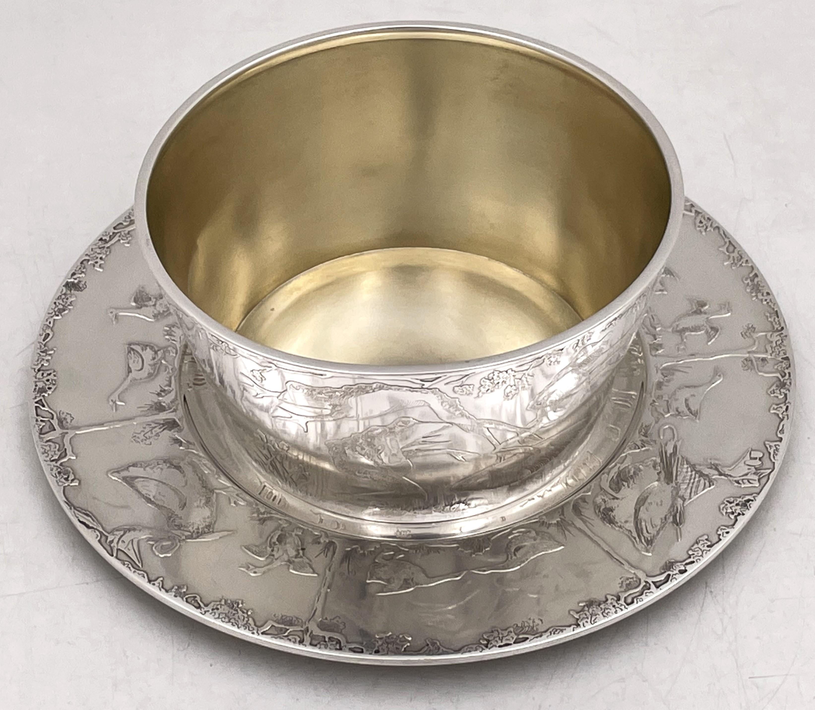 Frank W. Smith sterling silver bowl (gilt inside) and underplate, beautifully embossed with natural and animal motifs, including frogs, geese, and birds. The bowl measures 4 1/2'' in diameter by 2 1/3'' in height while the underplate measures 6