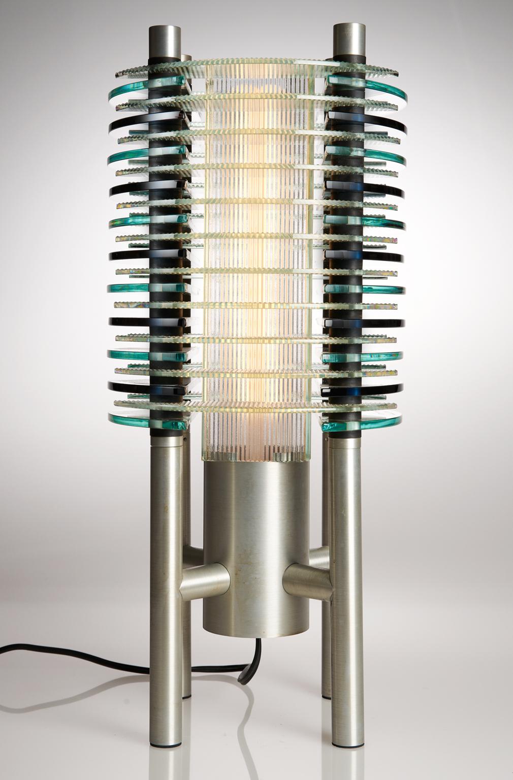 Create a bold statement with this table lamp, titled F-Stop Lamp, designed and created by Sidney Hutter Glass & Light. Originally designed in 1988, this work of art stands the test of time making a bold statement in today's contemporary setting. The