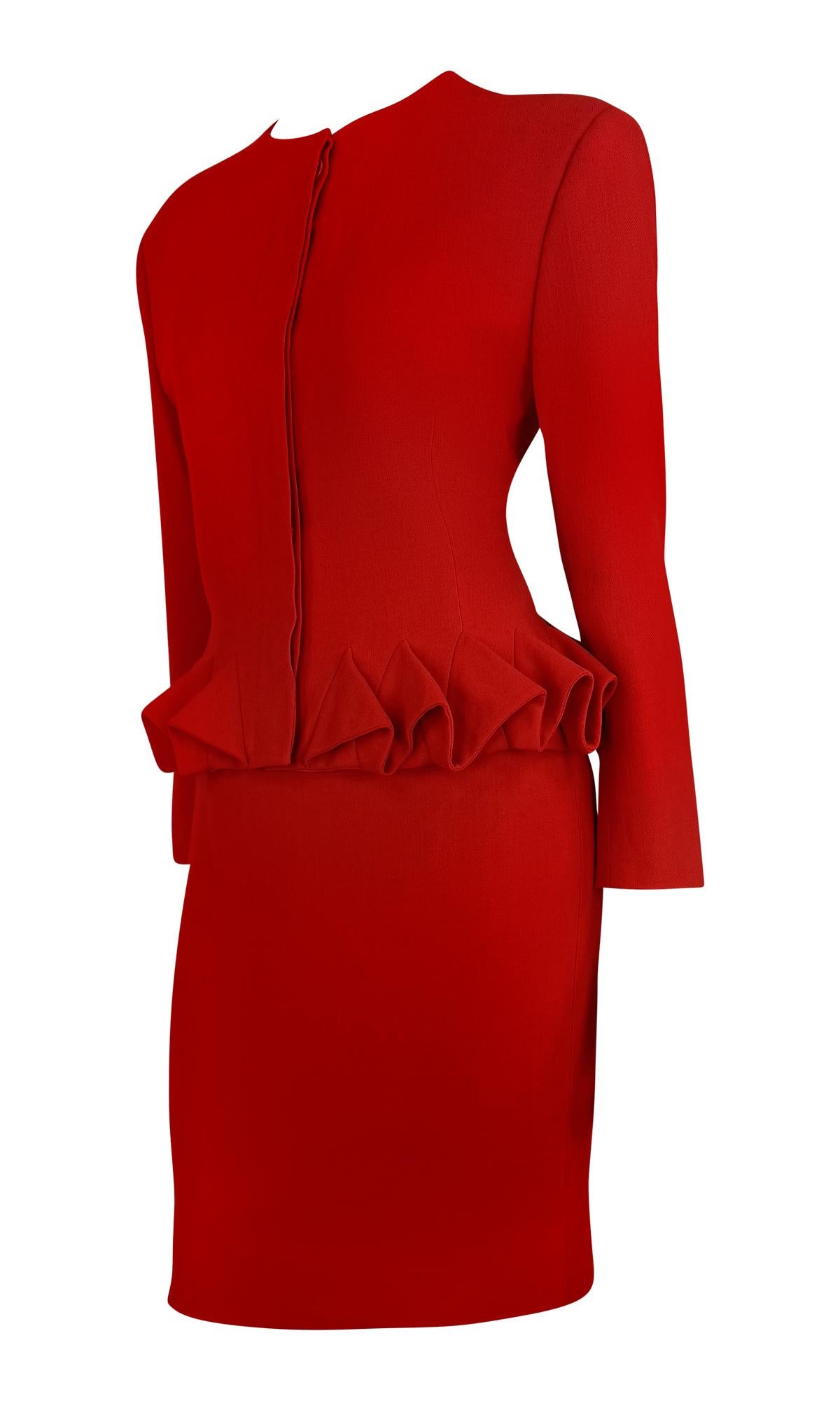 This Gianni Versace red wool skirt suit from the Fall/Winter 1988 collection showcases the designer's signature structured tailoring. The jacket features sharp shoulders, a fitted silhouette, and a dramatic folded flare peplum detail, adding a touch