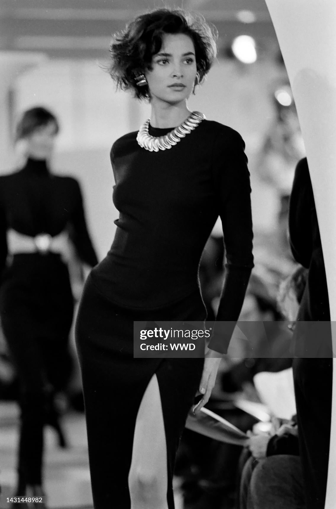 This Donna Karan navy blue stretch wool midi dress debuted on the Fall/Winter 1989 runway. This elegant design showcases a body-skimming silhouette with long sleeves and a high side slit, reflecting Karan's signature minimalist sophistication.