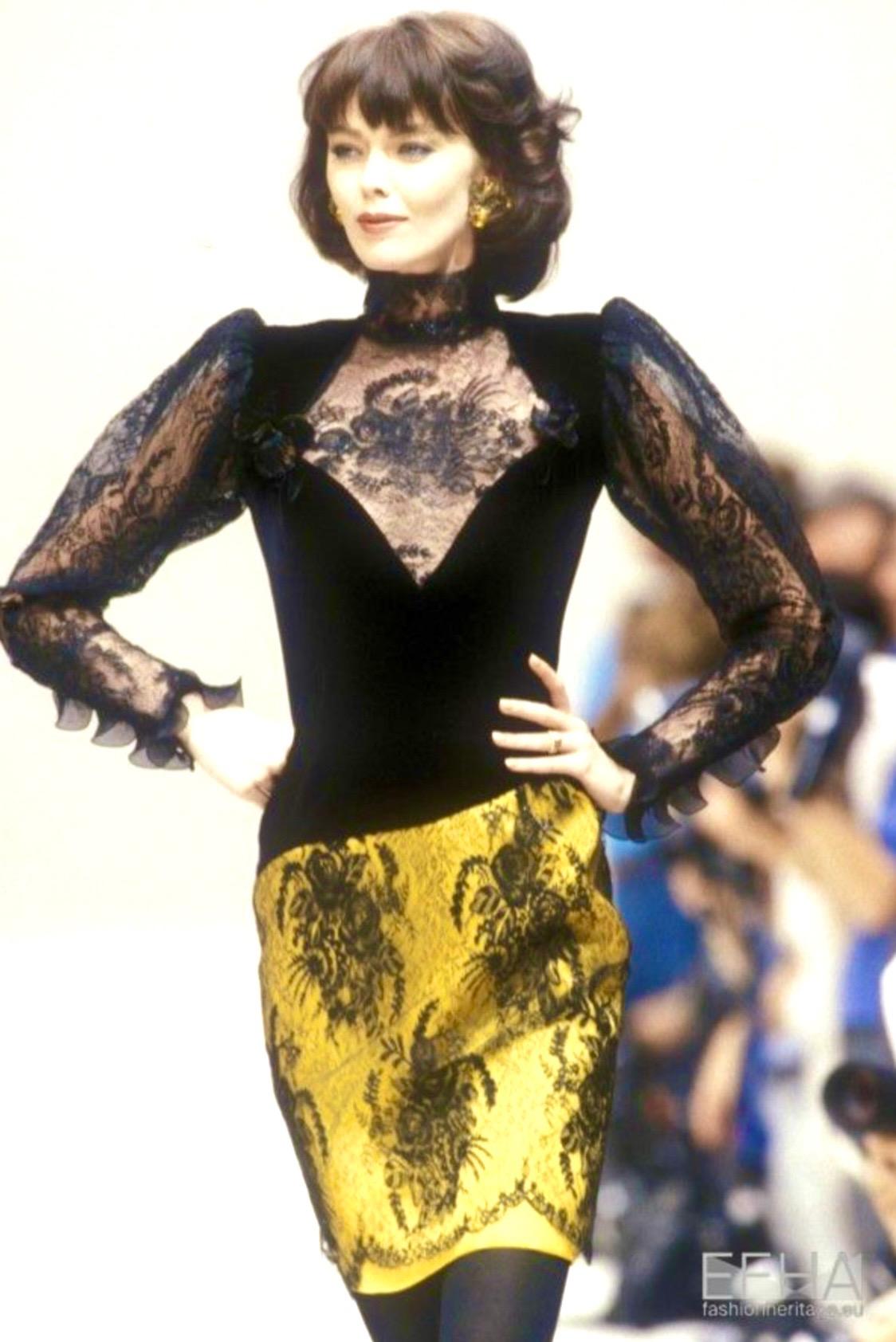 Presenting a lace, velvet, and yellow satin dress crafted for Emanuel Ungaro's Fall/Winter 1989 haute couture collection. The bold, structured silhouette is contrasted with the piece's delicate scalloped floral lace, left sheer at the neckline and