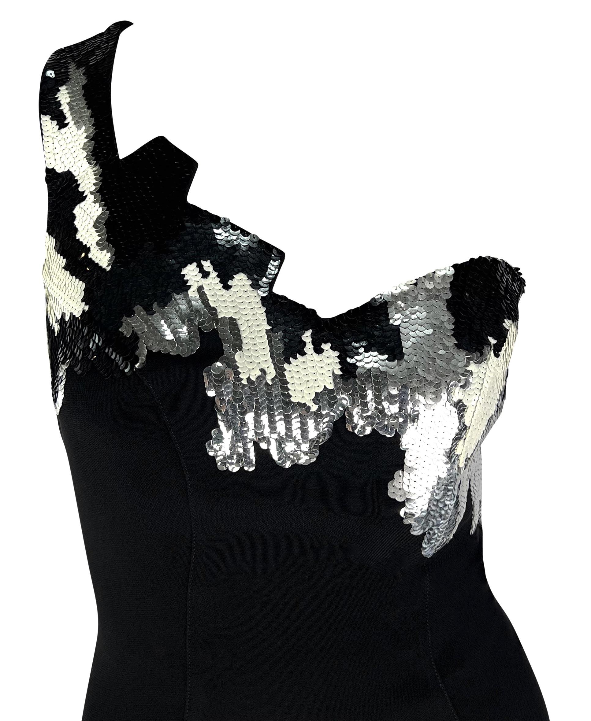 Manfred Mugler designed this stunning black Thierry Mugler mini dress for the Fall/Winter 1989 collection. This captivating dress features a single shoulder strap with an abstract angular cut bust accented with black, white, and silver sequins, with