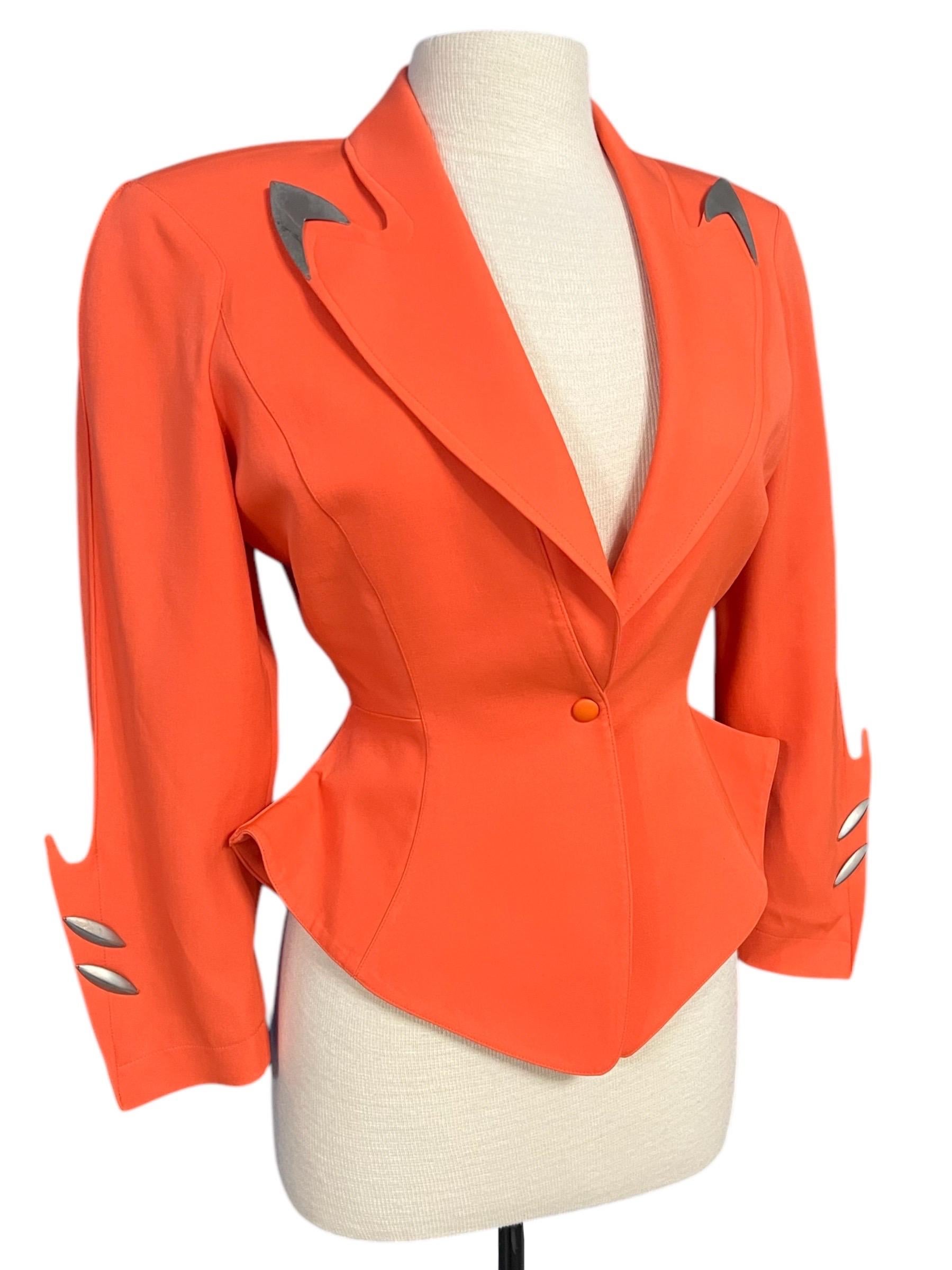 Chaqueta futurista Thierry Mugler de color naranja vivo de la colección Otoño-Invierno 1989 Hiver Buick.
Hombros estructurados, cintura acampanada con peplum, cierre con un solo botón a presión y mangas largas.
Las puntas de las solapas están