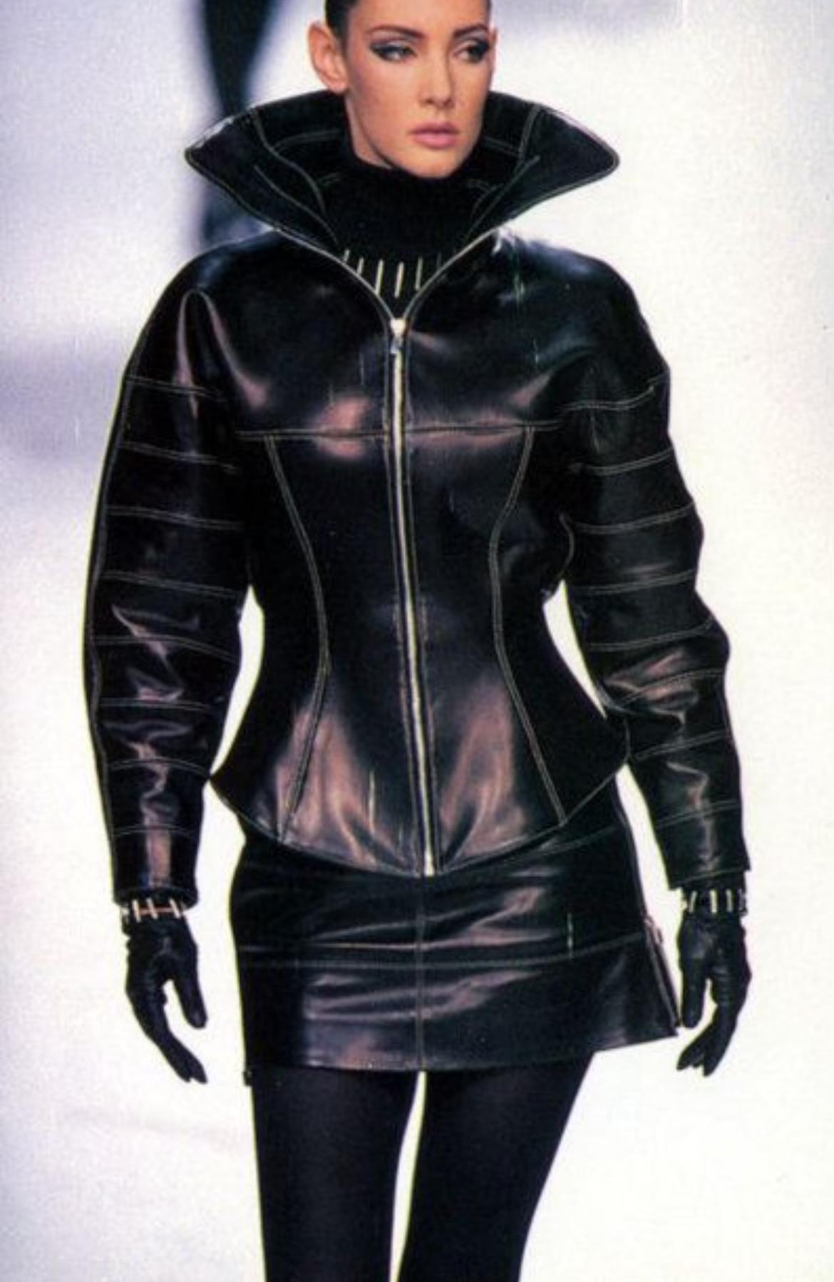 Te presentamos un increíble conjunto de traje de chaqueta y falda de moto Claude Montana de cuero negro. De la colección Otoño/Invierno 1991, este conjunto debutó en la pasarela de la temporada. Confeccionado íntegramente en cuero negro, el conjunto