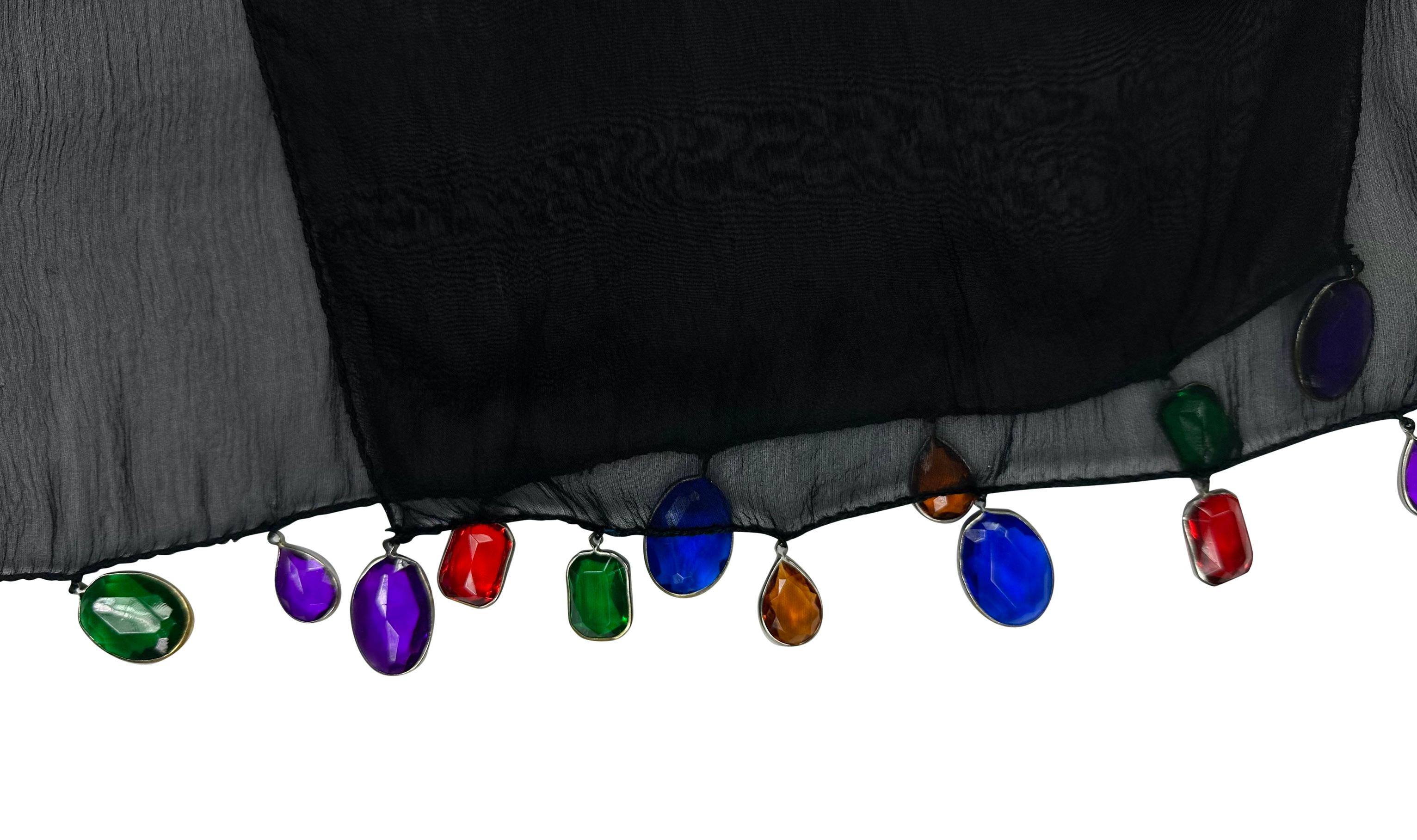 Questo foulard di Dolce & Gabbana della collezione Autunno/Inverno 1991 è realizzato in chiffon di seta nero trasparente, ornato con eleganza da gioielli di strass colorati lungo i bordi.

Misure approssimative:
Lunghezza: 54