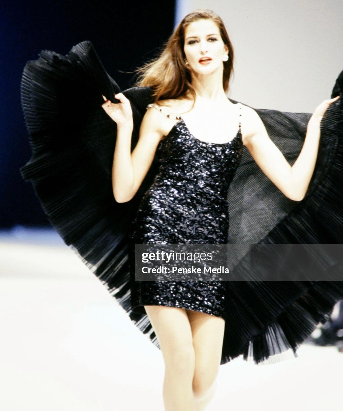 A version of this Gianfranco Ferré slip-style dress debuted on the Fall/Winter 1991 runway and features a scoop neckline and delicate rhinestoned bead straps. The dress is crafted from a stretch fabric with a shimmering textured finish.