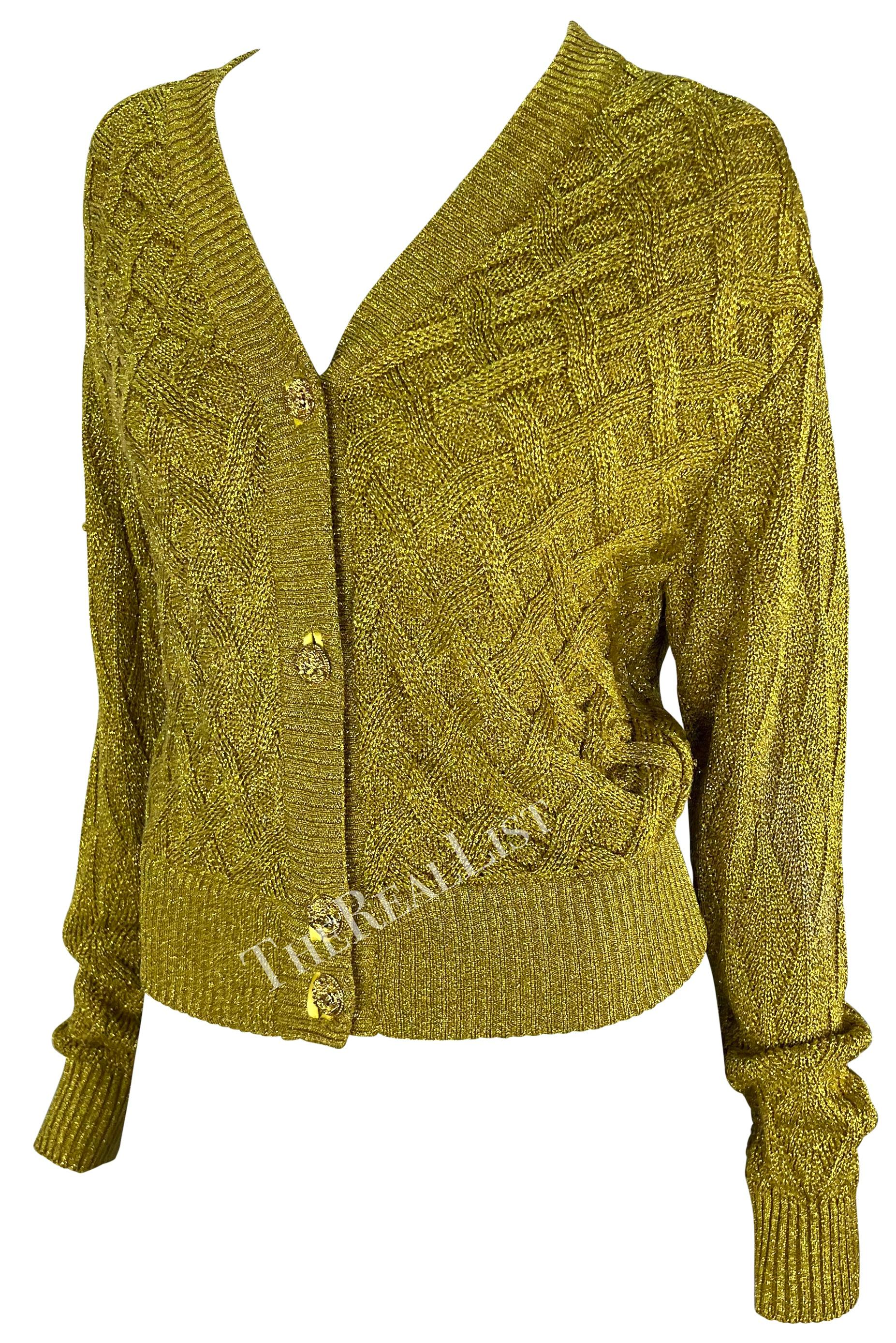 Présentation d'un pull cardigan Atelier Versace en maille câblée dorée, dessiné par Gianni Versace. Issu de la collection automne/hiver 1992, ce pull en maille métallique dorée présente une encolure en V et une fermeture boutonnée ornée de boutons