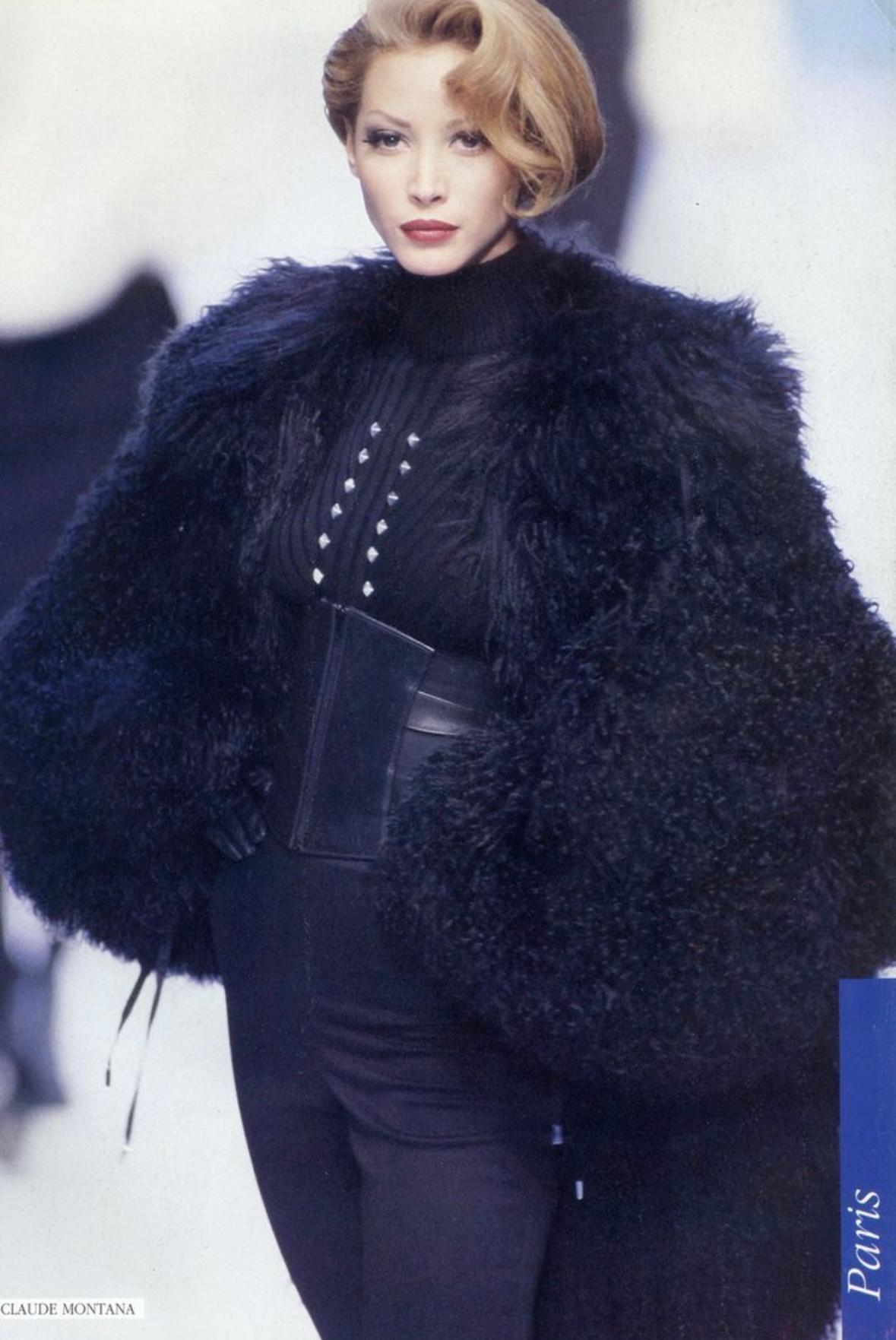 From the Fall/Winter 1992 Claude Montana collection, this oversized black shearling hooded jacket debuted on the season's runway, modeled by Christy Turlington-Burns. This voluminous coat features drawstrings at either cuff and the hem and is