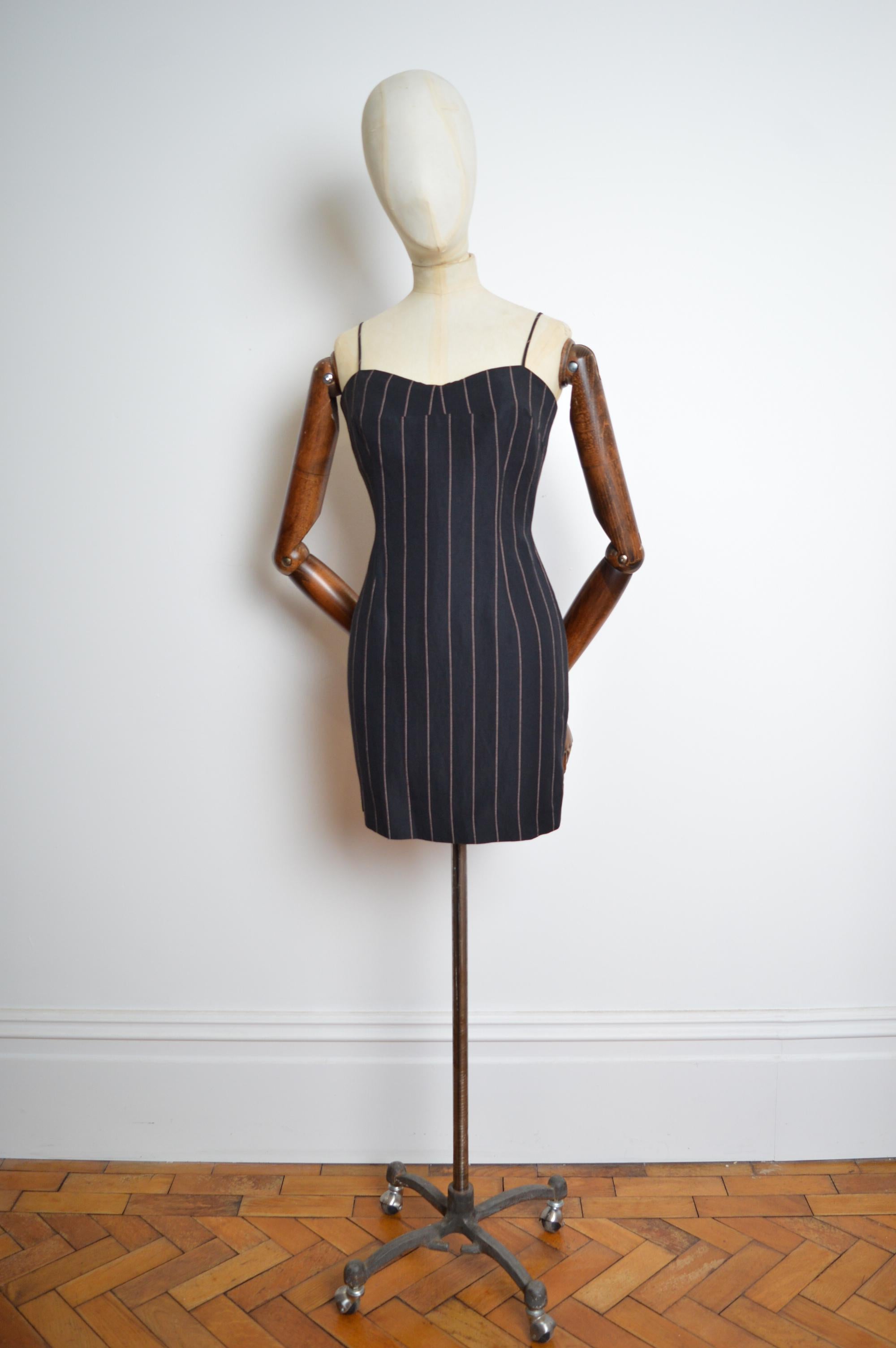 Favoloso ensemble da passerella di Dolce & Gabbana per l'autunno/inverno 1992, composto da un blazer doppiopetto in lino e da un abitino nero a righe gessate abbinato. Come indossata da Monica Bellucci in passerella. 
Caratteristiche: Mini abito con