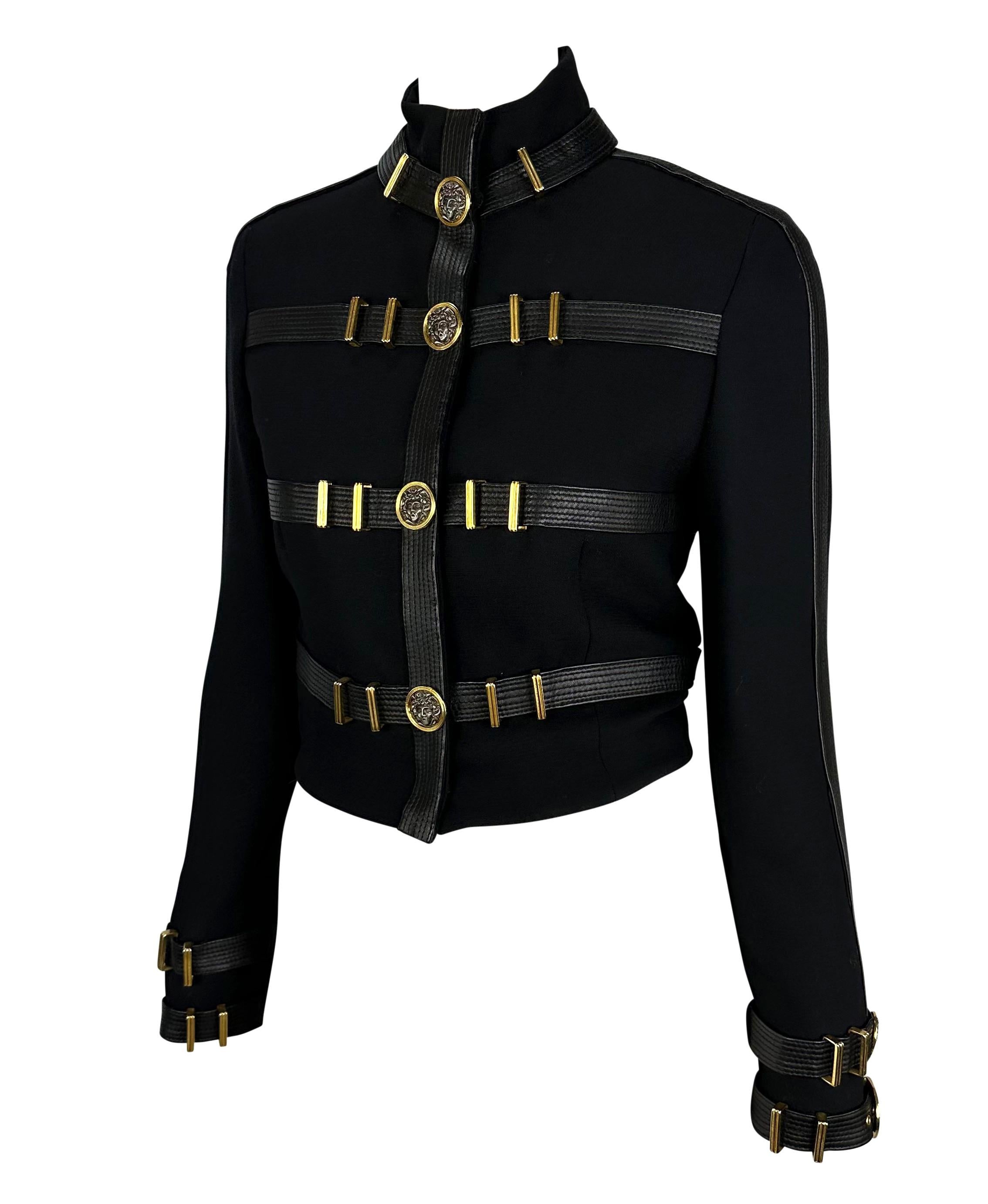 Presenting the most incredible leather accented bondage buckle Gianni Versace cropped jacket, designed by Gianni Versace. From the Fall/Winter 1992 'Miss S&M' collection, this jacket features quilted leather straps at the body and cuffs. Each