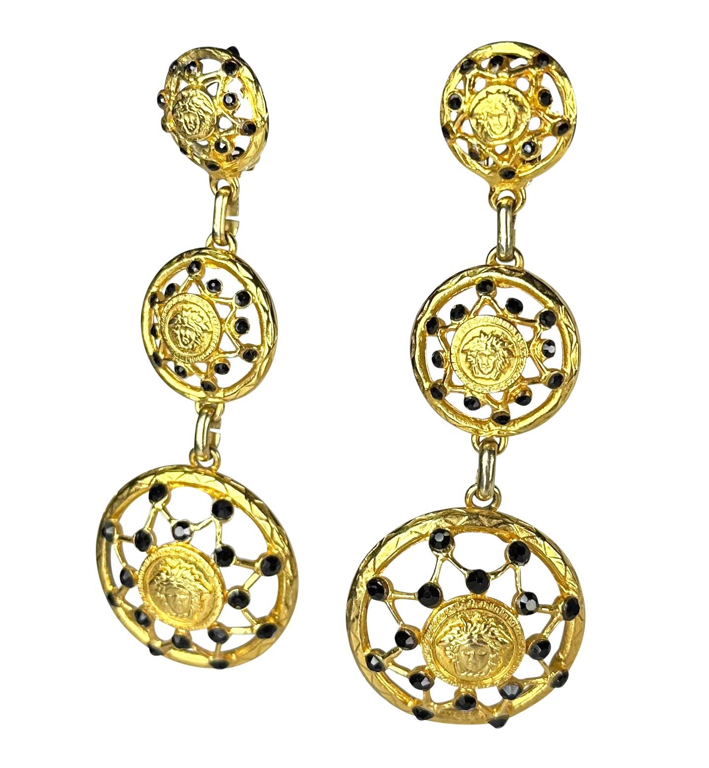 Presenting a pair of gold-tone Gianni Versace drop earrings, designed by Gianni Versace. From the Fall/Winter 1992 'Miss S&M' collection, these truly incredible clip-on earrings feature a Versace Medusa logo at the center of each circle surrounded
