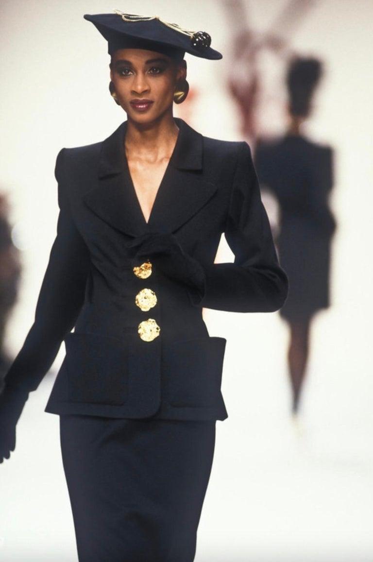 Presenting a striking black blazer from Yves Saint Laurent’s Fall/Winter 1992 collection. Modeled on the season’s runway by Gloria Burgess, this sculpted blazer is defined by dramatic lapels, oversized patch pockets, and large bold gold textured