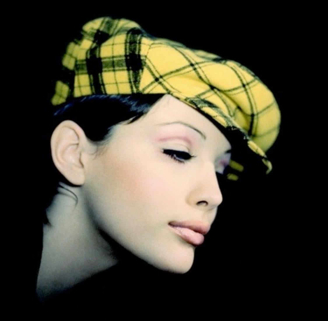 Hier wird ein von Gianni Versace Couture entworfener, gelb karierter Hut im Paperboy-Stil präsentiert. Dieser übergroße Papierboyhut aus der Herbst/Winter-Kollektion 1993 besteht aus zwei verschiedenen Flanellmustern und hat eine kleine Krempe. Wie