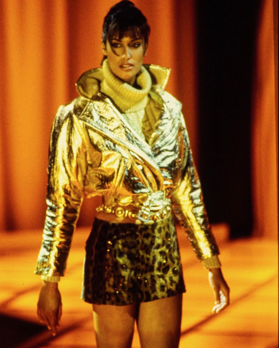 TheRealList presents: an incredible gold-colored Gianni Versace turtleneck sweater, designed by Gianni Versace. From the Fall/Winter 1994 collection, this sweater debuted on the season's runway as part of look 71 modeled by Yasmeen Ghauri. Similar