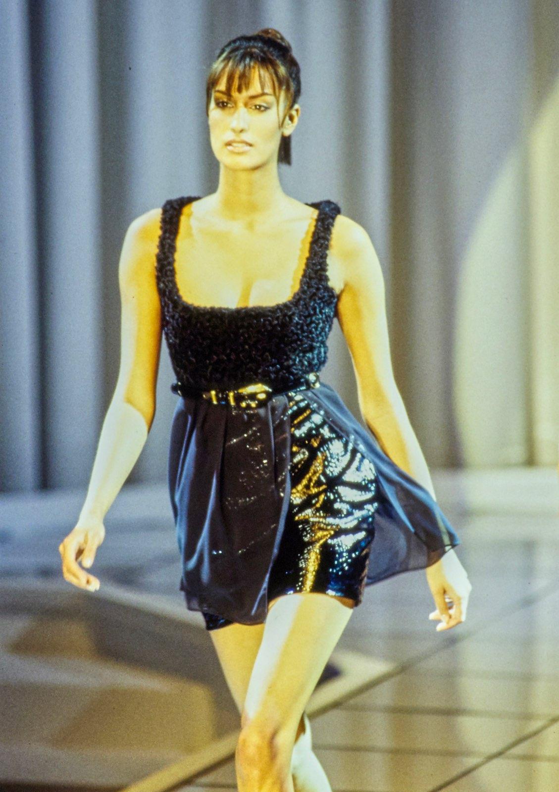 Presenting F/W 1994 Gianni Versace runway - a mix of playfully sexy and high-tech. An iteration of this dress designed by Gianni Versace was debuted as look 53 and was worn by Yasmeen Ghauri. This black dress comes across as a full ensemble made of