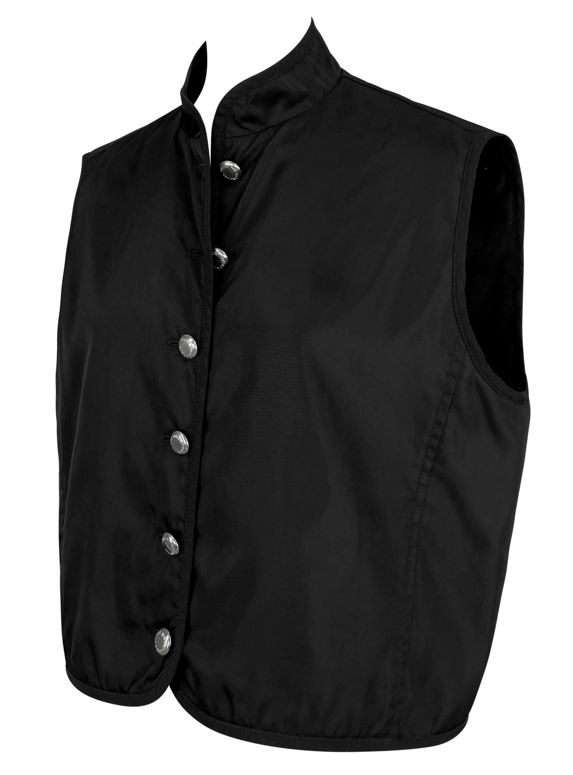 This oversized black nylon Prada vest from the Fall/Winter 1994 collection features a high Nehru-style collar and round, silver-tone button closures. Its minimalist design is enhanced by a boxy, slightly cropped silhouette, giving it a modern,