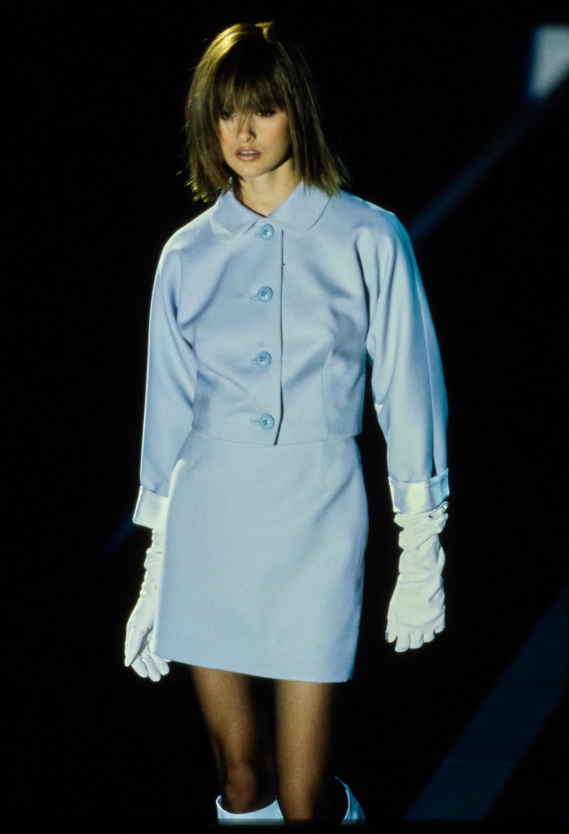 Ti presentiamo uno splendido tailleur con gonna Gianni Versace Couture di colore azzurro, disegnato da Gianni Versace. Questo set ha debuttato sulla passerella Autunno/Inverno 1995 come look numero 23 di Trish Goff. Una versione su misura di questo
