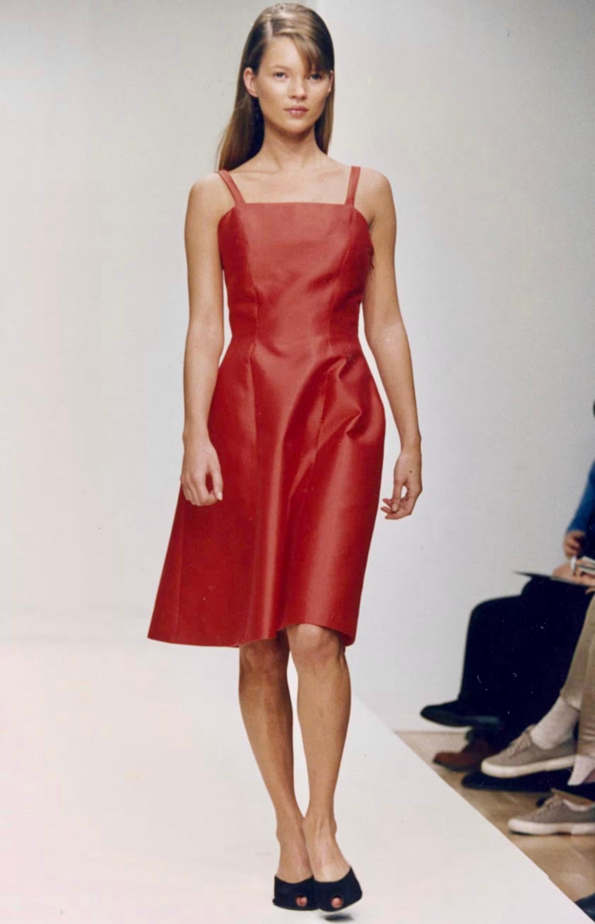 Kate Moss modeled this fabulous red Prada mini dress on the brand's Fall/Winter 1995 runway as look 53. Constructed of a silk/wool taffeta, this sleek mini dress features thin straps, a square neckline, and a flared skirt. Effortlessly chic and
