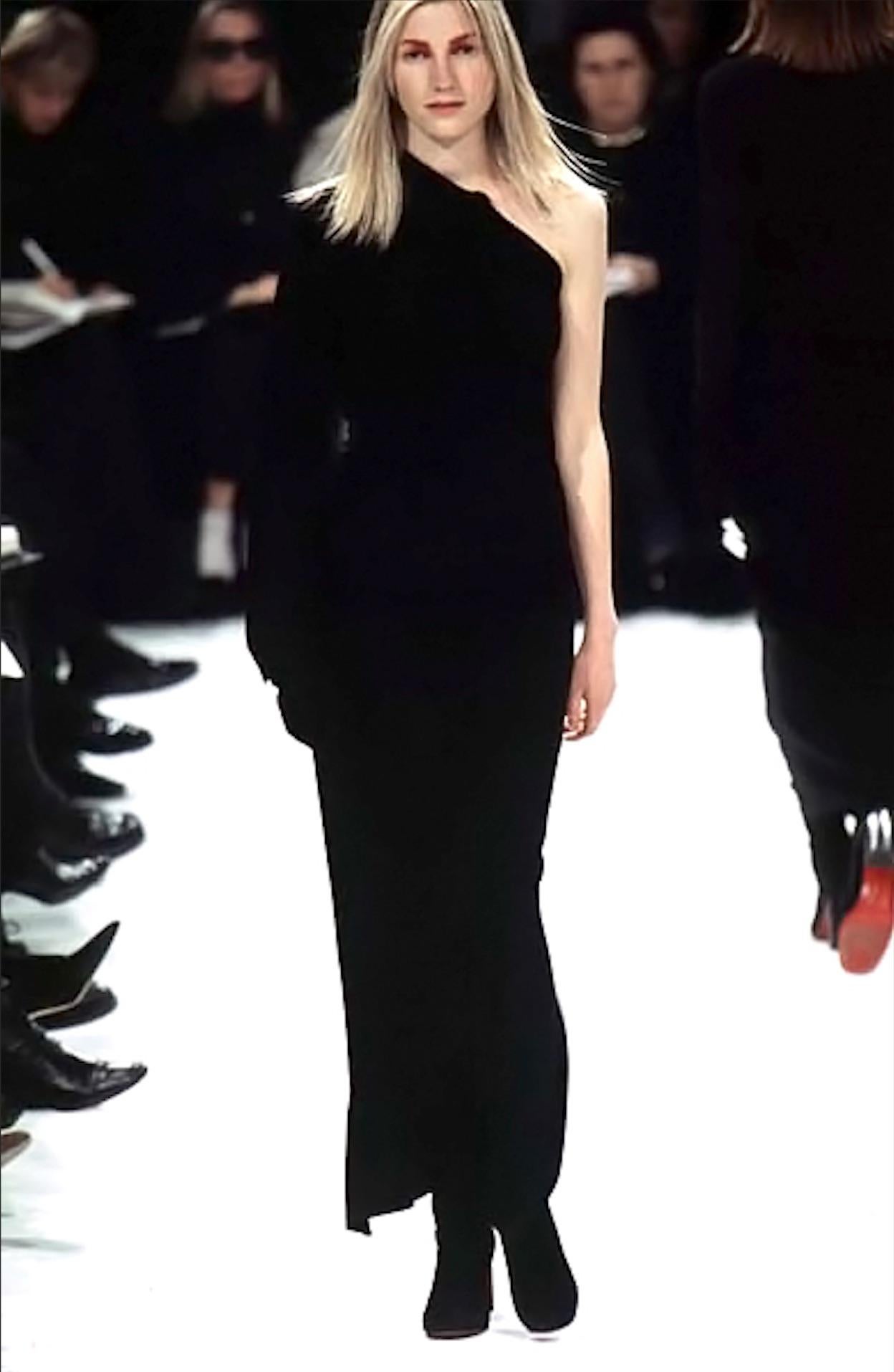Issue de la collection automne/hiver 1996 d'Ann Demeulemeester, cette robe en stretch noir présente un col montant asymétrique et une fermeture à bouton spectaculaire qui s'étend de l'encolure à l'ourlet. Présentée sur le défilé de la saison, cette