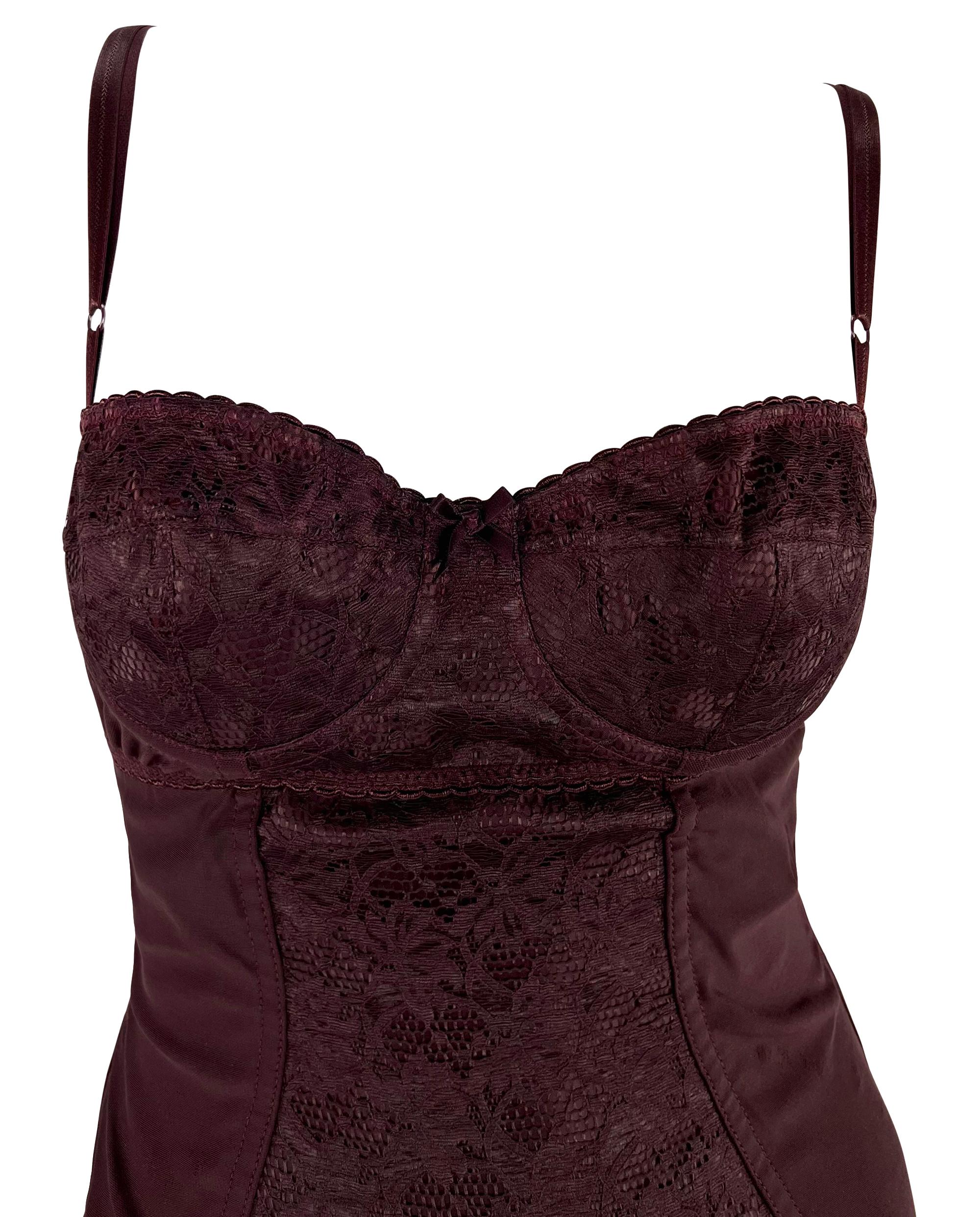 This burgundy Dolce & Gabbana lace bodysuit from the Fall/Winter 1996 collection features intricate lace detailing, a sweetheart neckline, and sheer accents throughout. A petite bow between the cups adds a touch of allure to this sexy