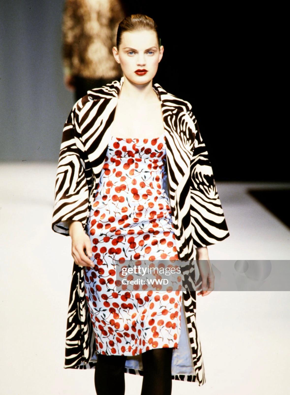 This iconic Dolce & Gabbana satin dress, adorned with a cherry print on a light blue background, is from the Fall/Winter 1996 collection. It debuted on the runway on Guinevere Van Seenus and was also featured in the season's ad campaign on Shirley