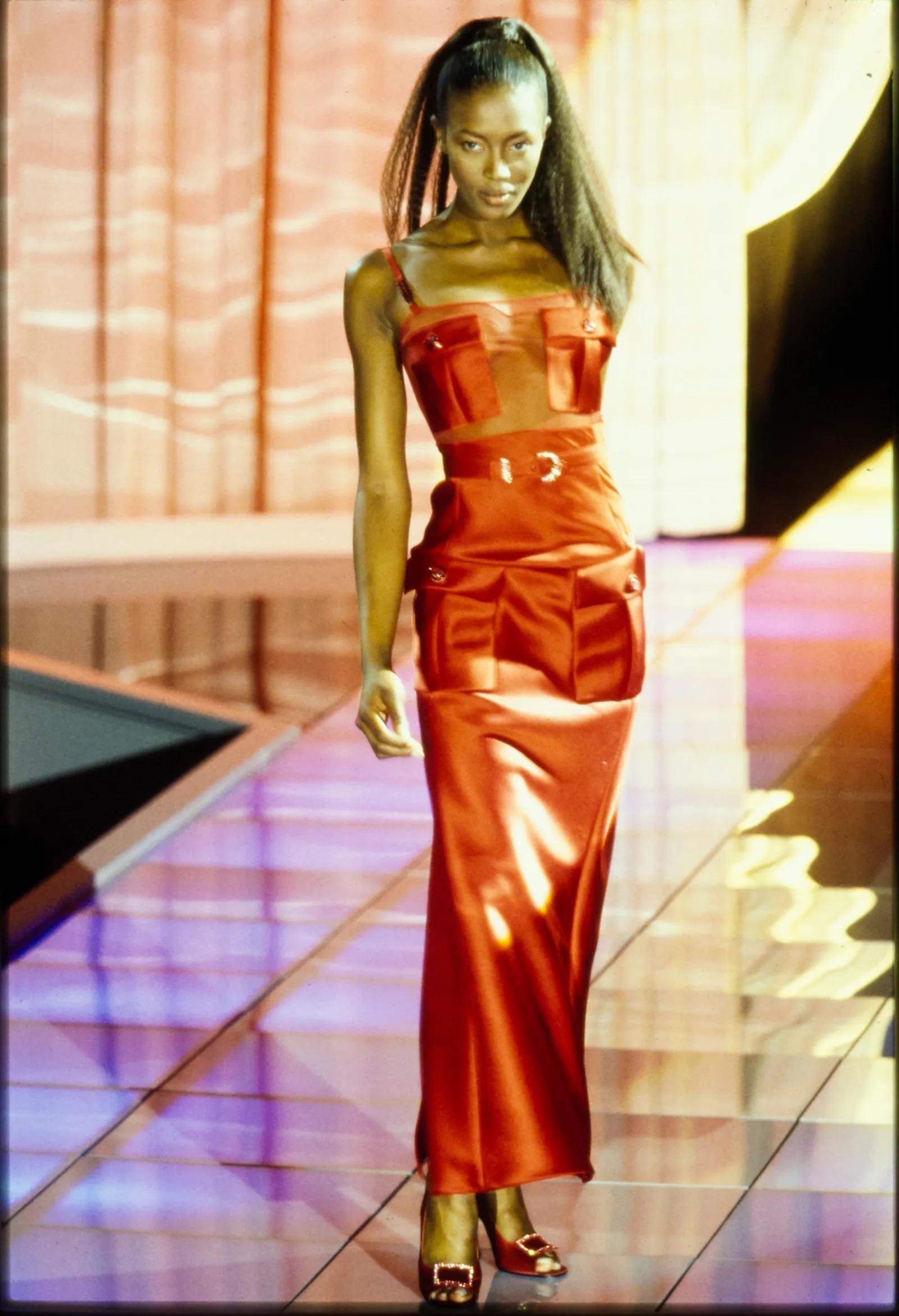 Presenting an incredible black satin Gianni Versace gown, designed by Gianni Versace. From the Fall/Winter 1996 collection, a belted version of this dress debuted in red on the season's runway modeled by Naomi Campbell. This fabulous gown is
