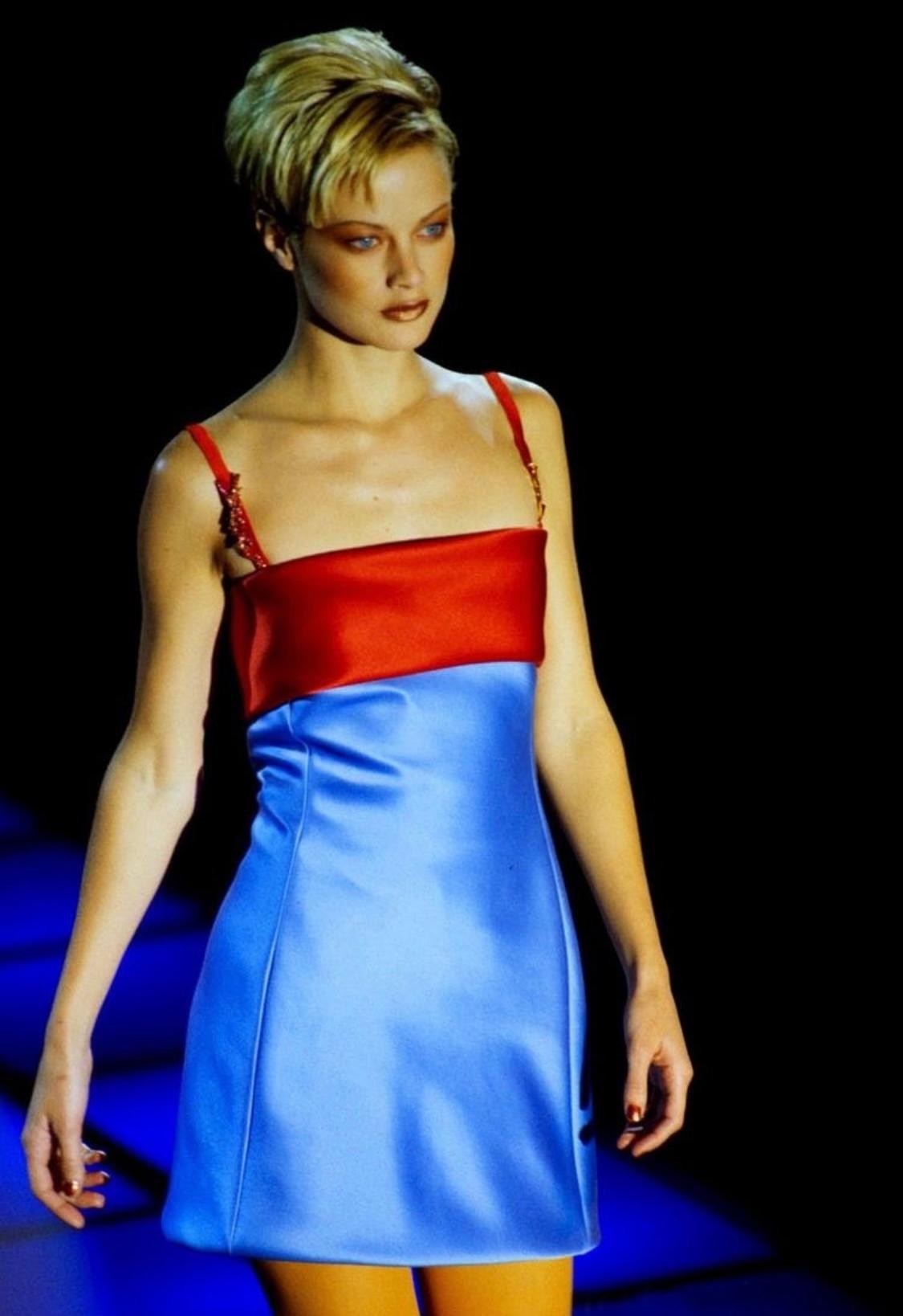 Réalisée en satin bleu vif et rouge, cette magnifique mini robe automne-hiver 1996 au motif coloré a été créée par Gianni Versace. Ce look a fait ses débuts en tant que look 42 sur le défilé F/W 1996 et a été porté par Carolyn Murphy. S'écartant de