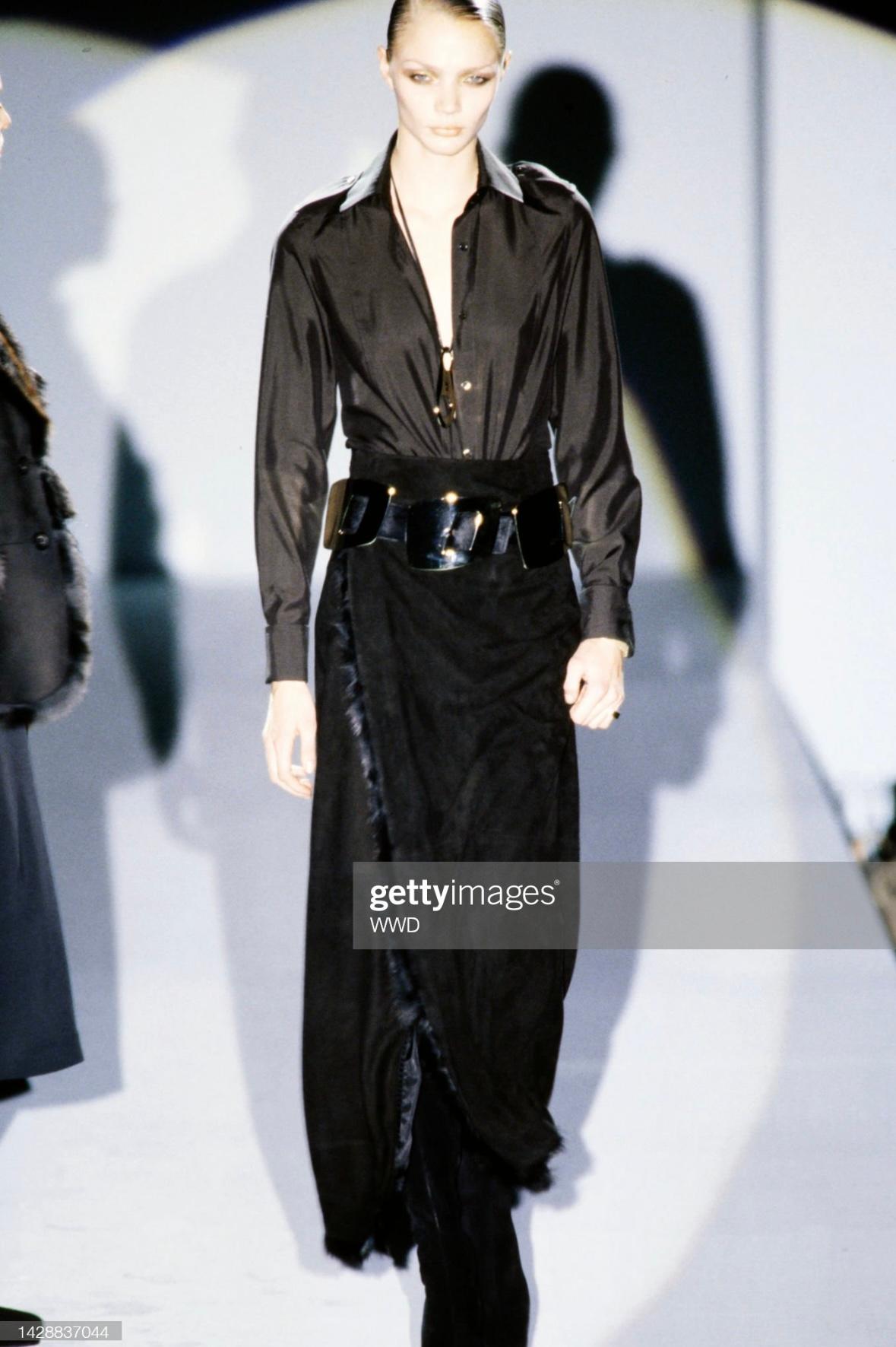 Je vous présente une incroyable jupe portefeuille maxi Gucci en daim noir, dessinée par Tom Ford. Issue de la collection Automne/Hiver 1996, cette jupe a fait ses débuts sur le podium dans le look 37, porté par Jodie Kidd. Cette fabuleuse jupe