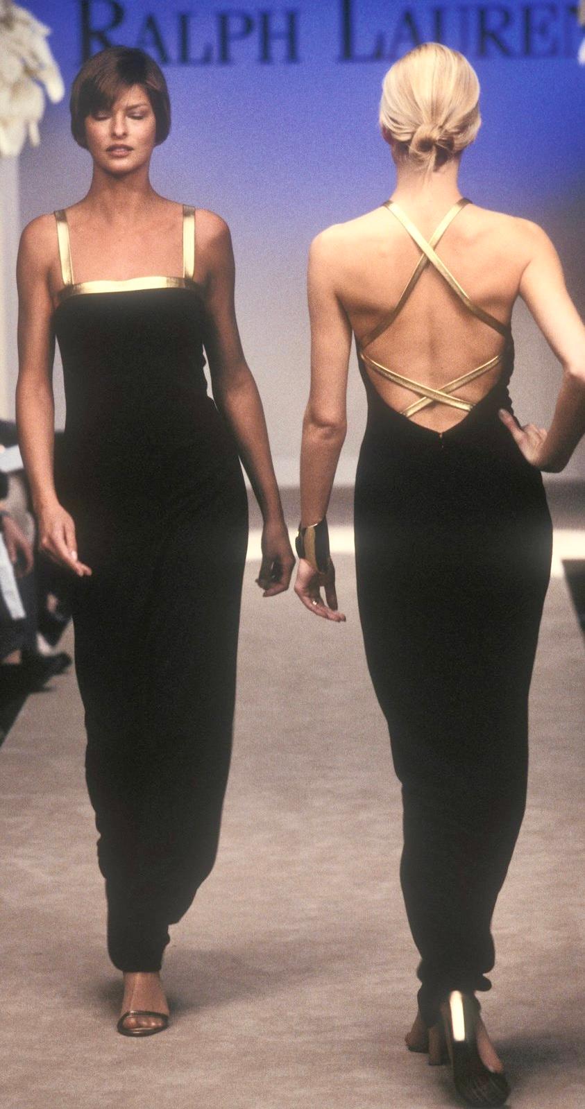 From Ralph Lauren's Fall/Winter 1996 collection, this black bodycon evening gown features a high neckline and a dramatic backless design with crisscrossing straps. A version of this gown with a gold leather strap debuted on the season's runway,