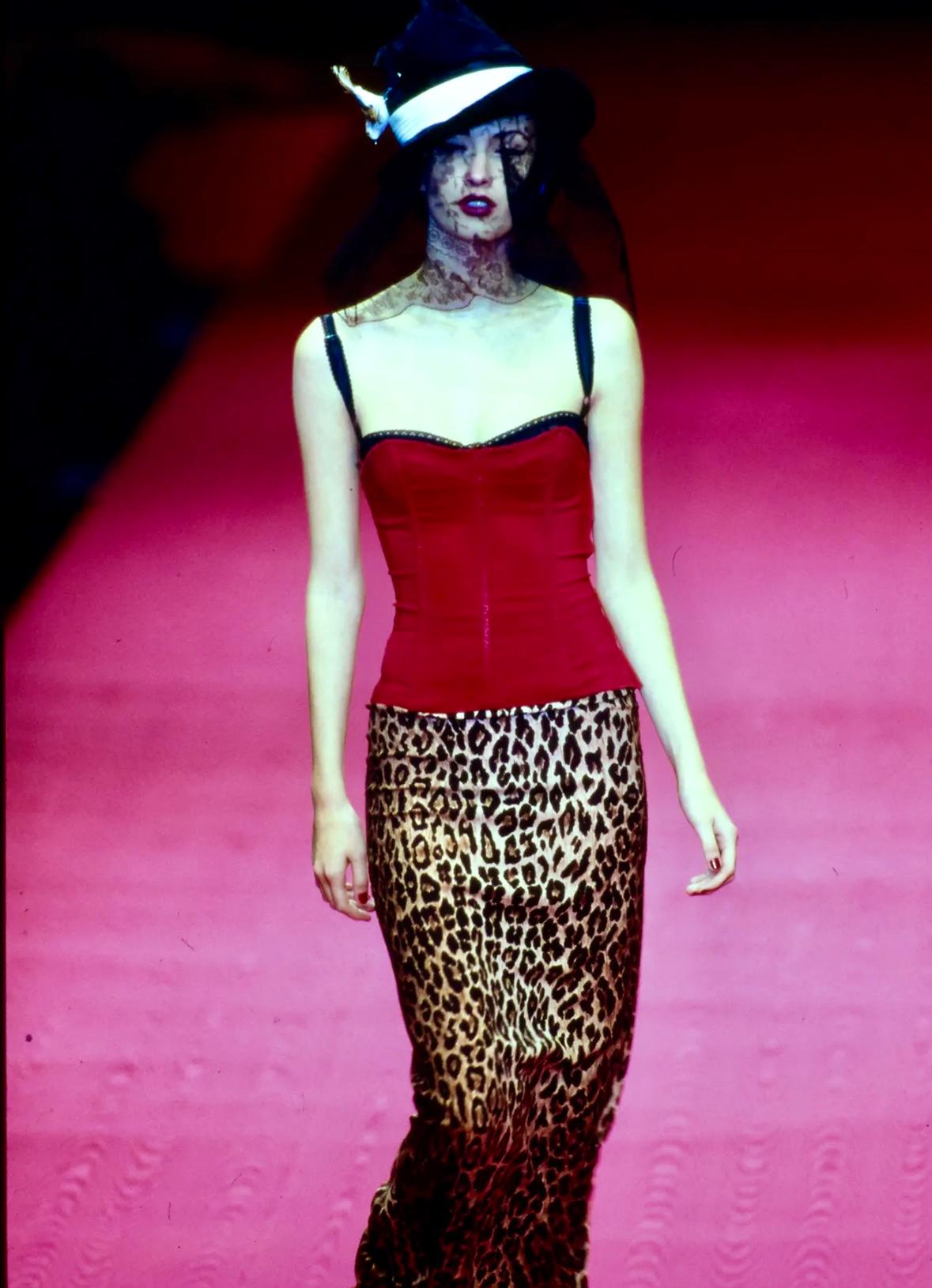 From Dolce & Gabbana’s Fall/Winter 1997 collection, this corset-inspired bustier top features structured boning and a striking red and black colorway. Designed with a built-in black lace bra, the piece blends lingerie elements with sculptural