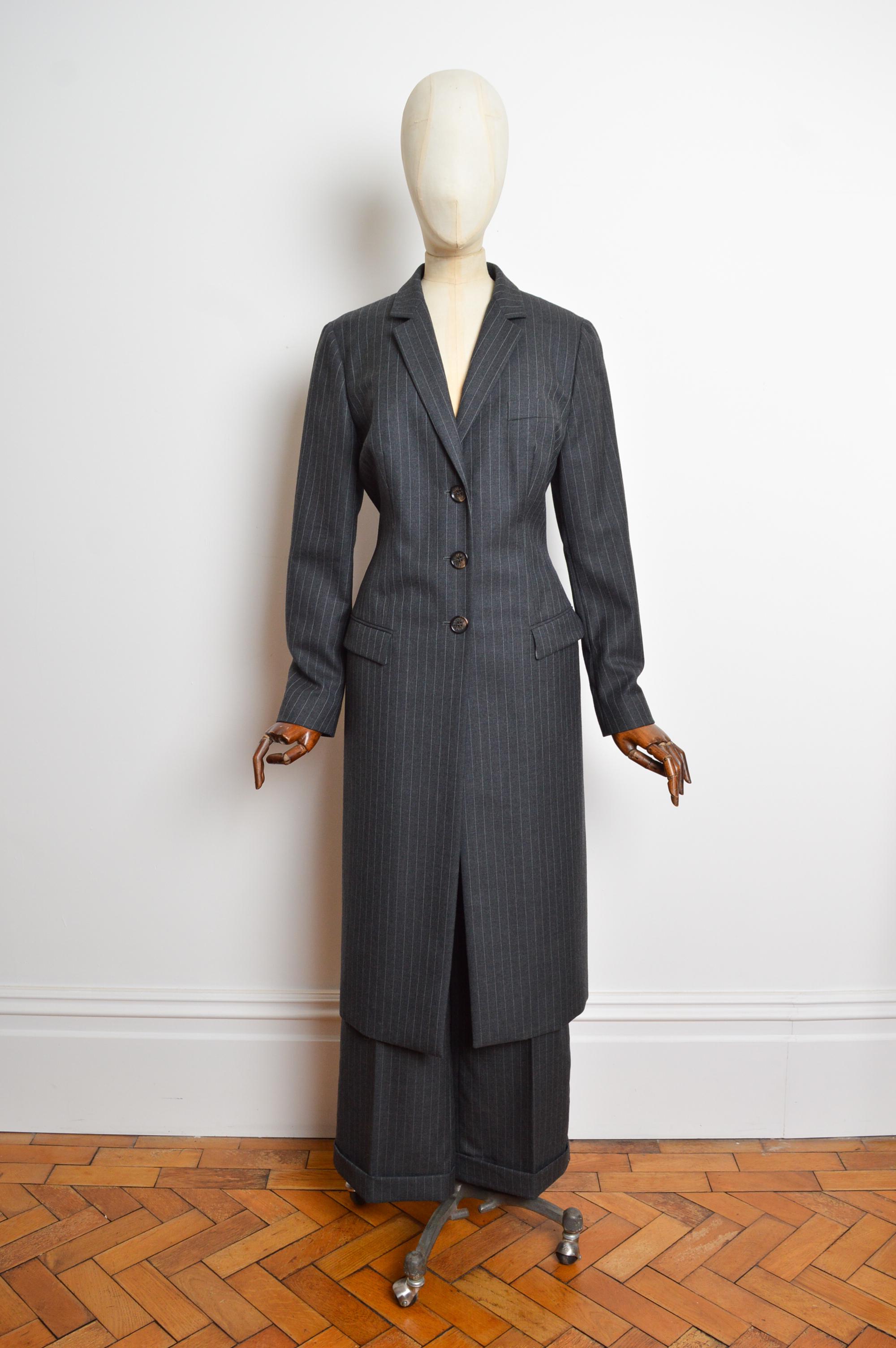 Un favoloso abito gessato autunno/inverno 1997 di Dolce & Gabbana. 
Caratterizzato da un blazer lungo e sartoriale con bottoni sul davanti e da pantaloni a vita alta abbinati con una piega decisa lungo la gamba. 
Taglia consigliata; K.K. 12
Le
