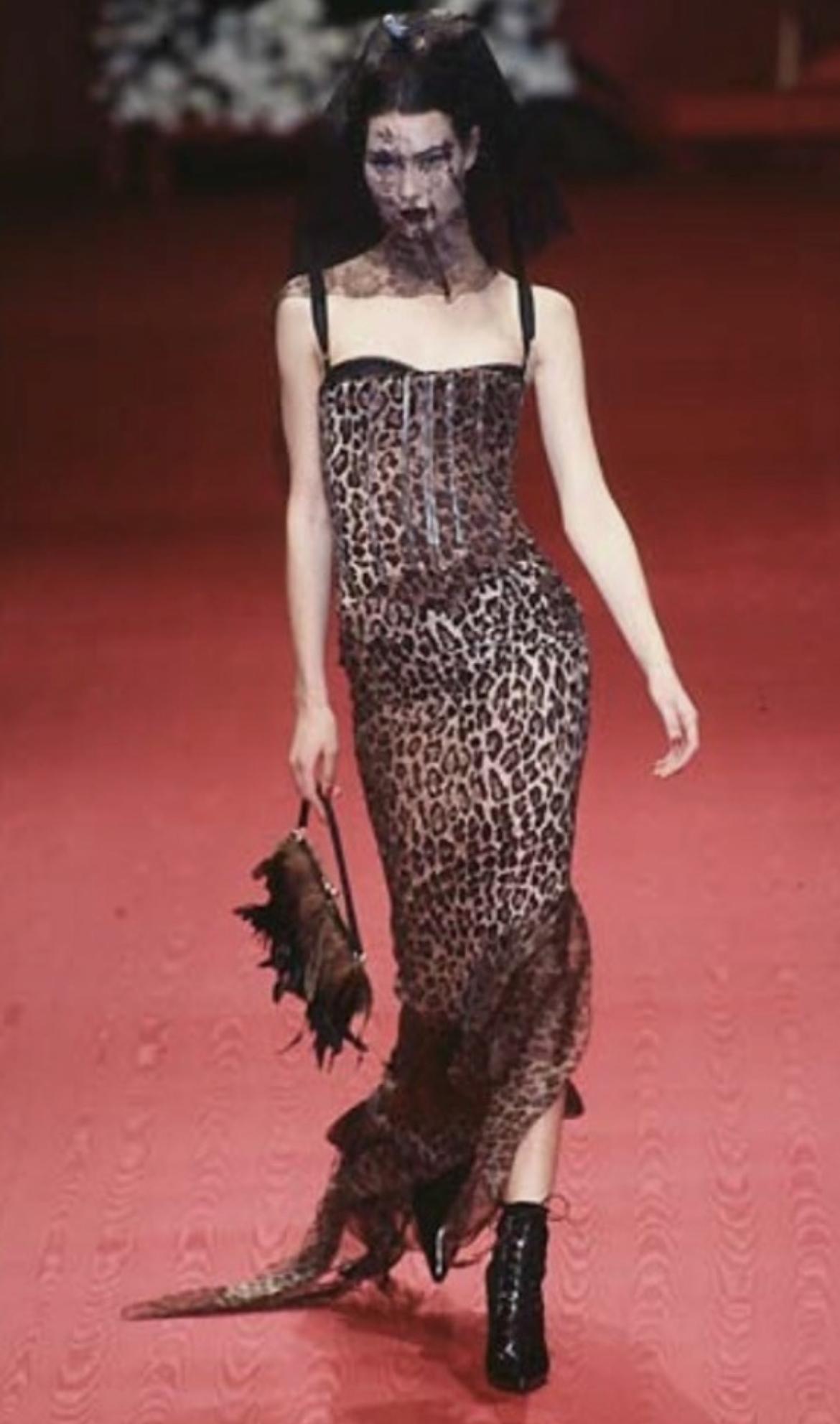 Presentamos un bolso de noche Dolce & Gabbana de satén negro y plumas marrones. De la colección Otoño/Invierno 1997, este bolso debutó en la pasarela de la temporada. El diseño está adornado con un prominente cierre de besos en tono plateado, una