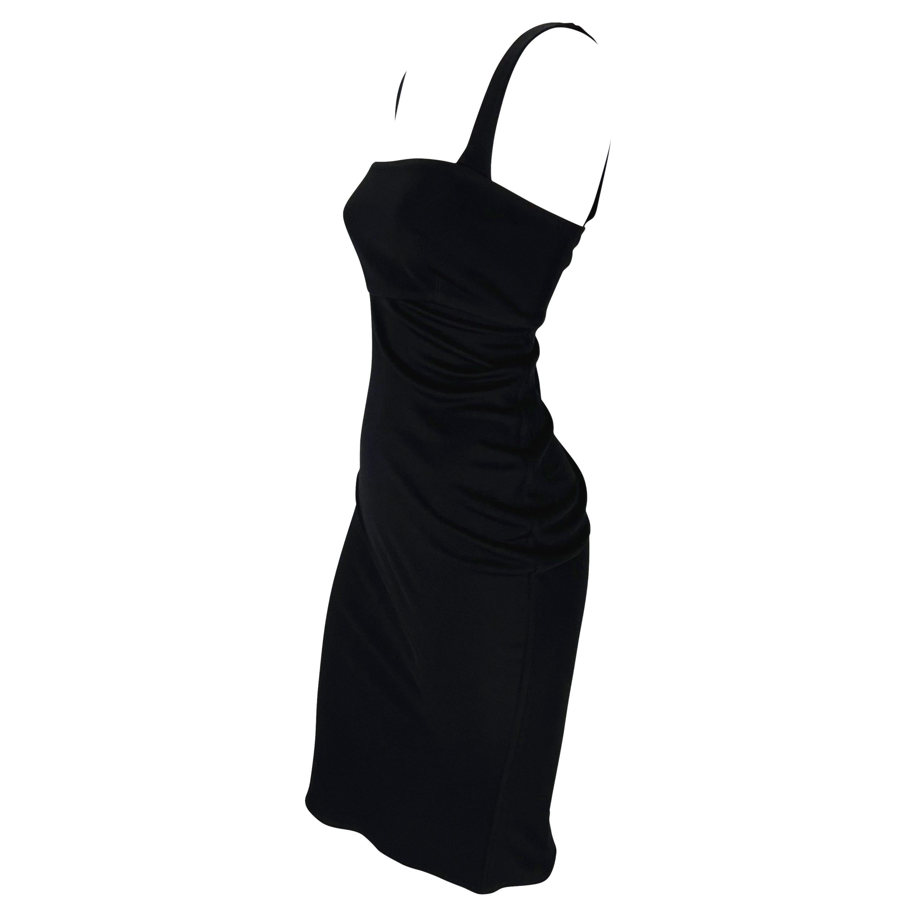 Présentation d'une sensuelle robe de cocktail noire Gianni Versace, créée par Gianni Versace. Issue de la collection automne/hiver 1997, cette petite robe noire présente de larges bretelles et une encolure carrée. La robe est complétée par une coupe