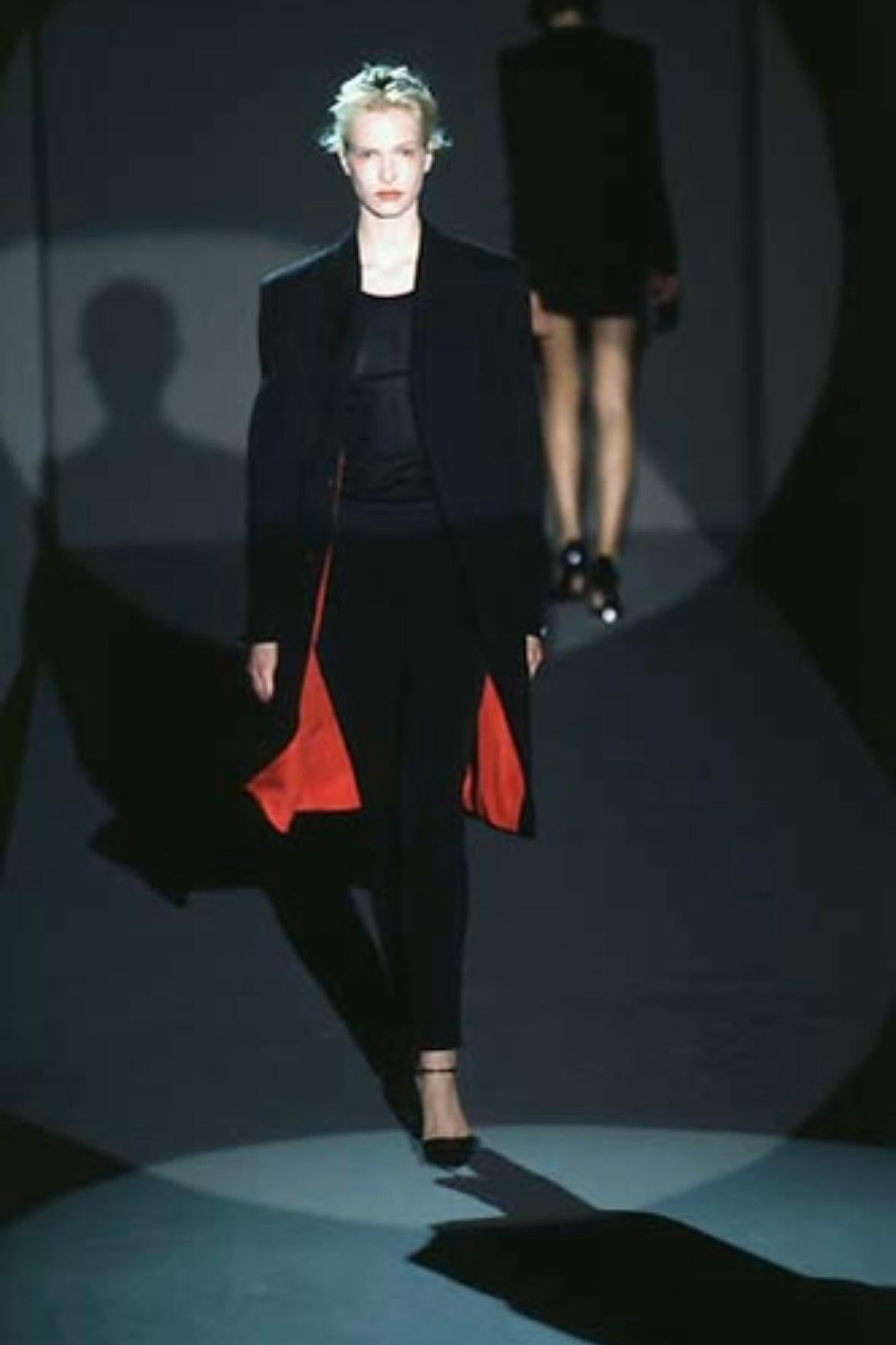 Présentation d'un fabuleux manteau long noir de Gucci, conçu par Tom Ford. Issu de la collection automne-hiver 1997, cet incroyable manteau se ferme par un bouton dissimulé sur le devant, comporte des poches sur les hanches et est complété par des